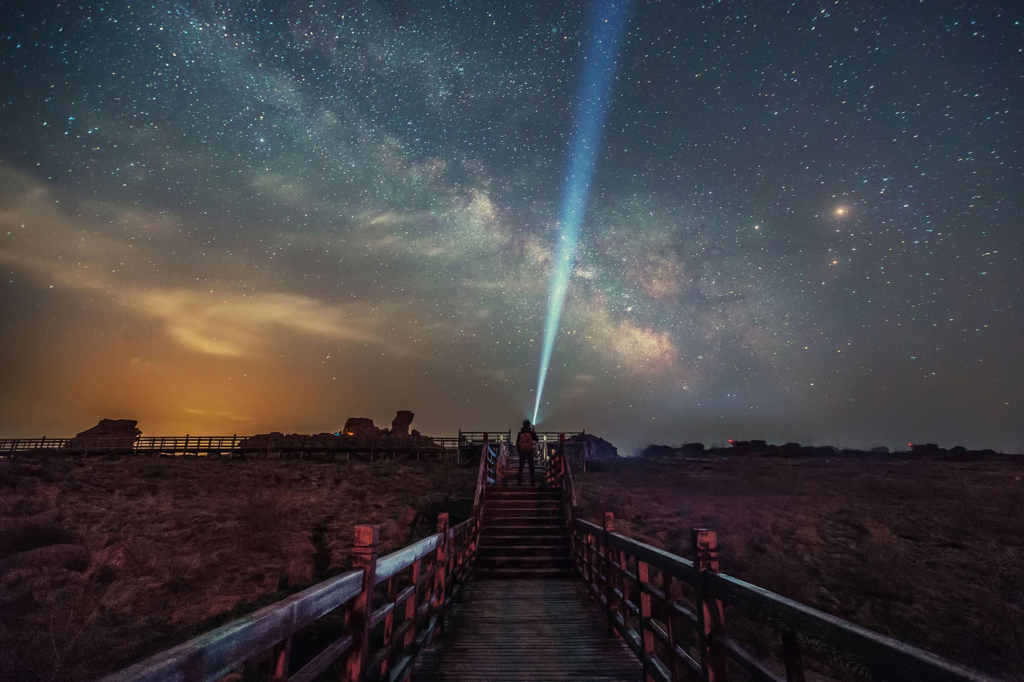 Man shining flashlight at sky on boardwalk in desert, Hebei, China, Man shining flashlight at sky on boardwalk in desert, Hebei, Chi