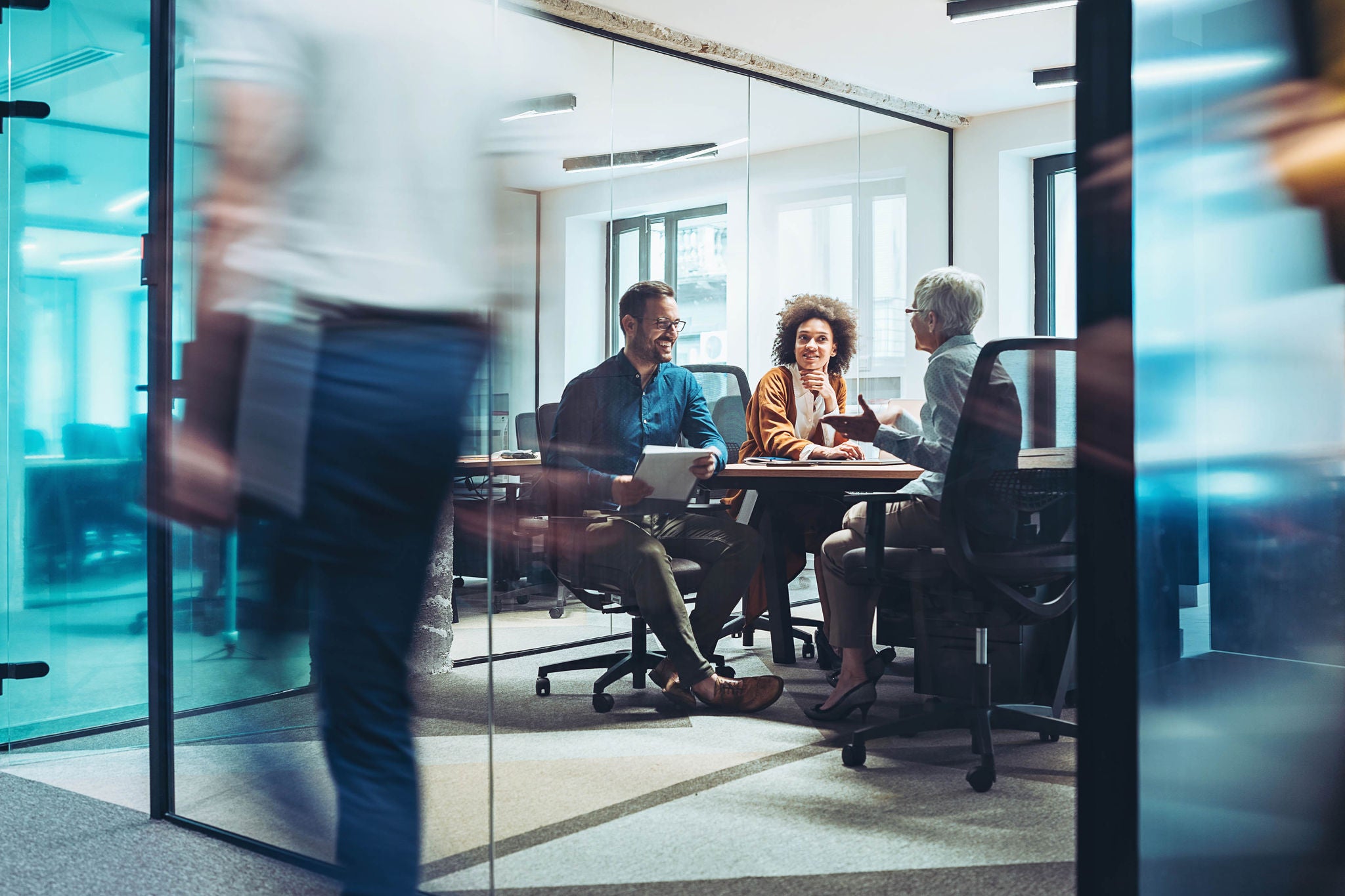 Group of business persons having a meeting in a closed glass conference room