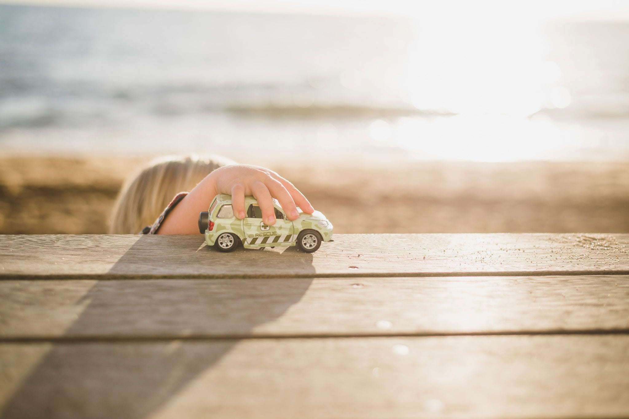 kid playing with toy car by the beach