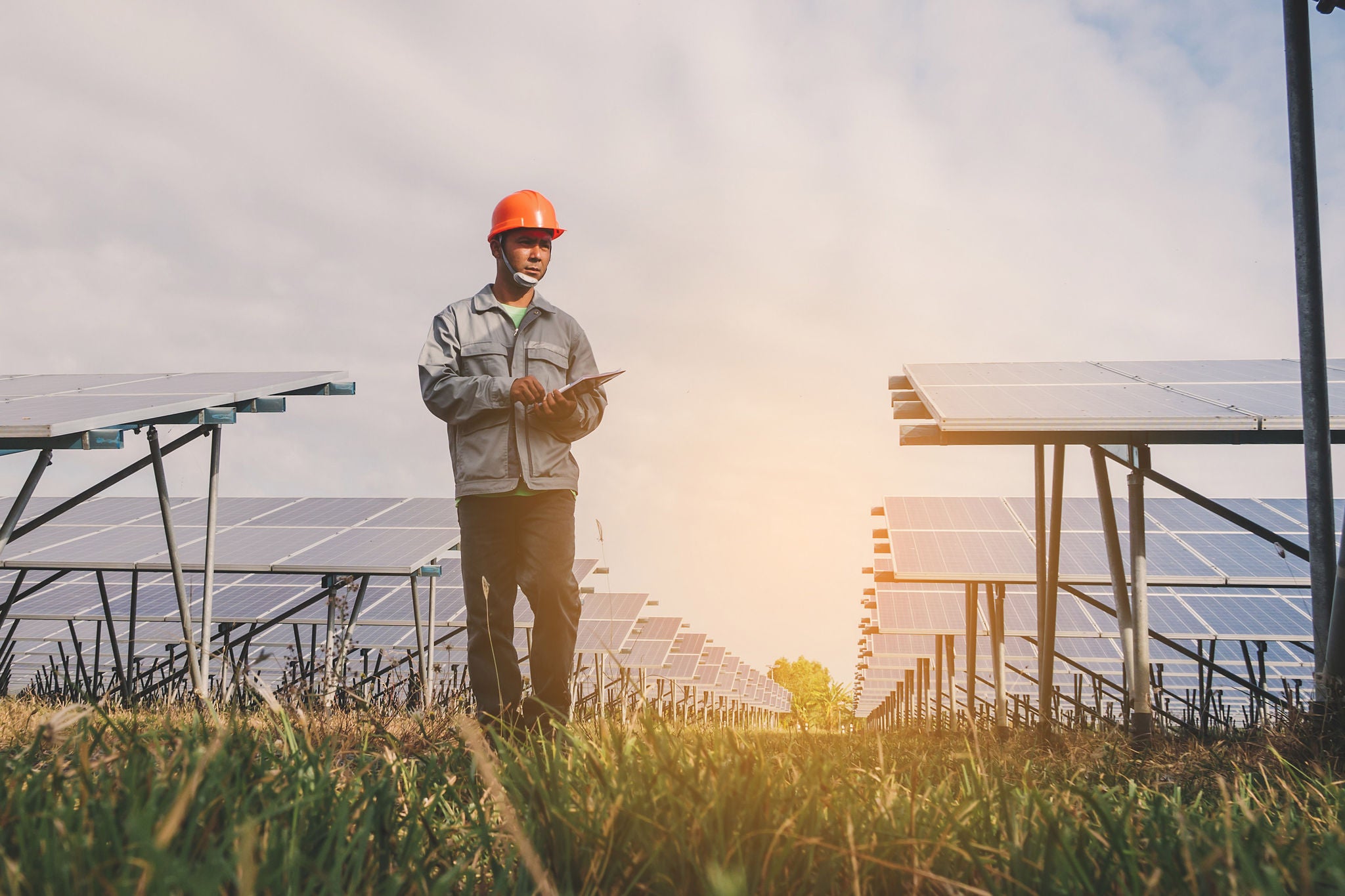 A man in a red helmet working at a solar power plant