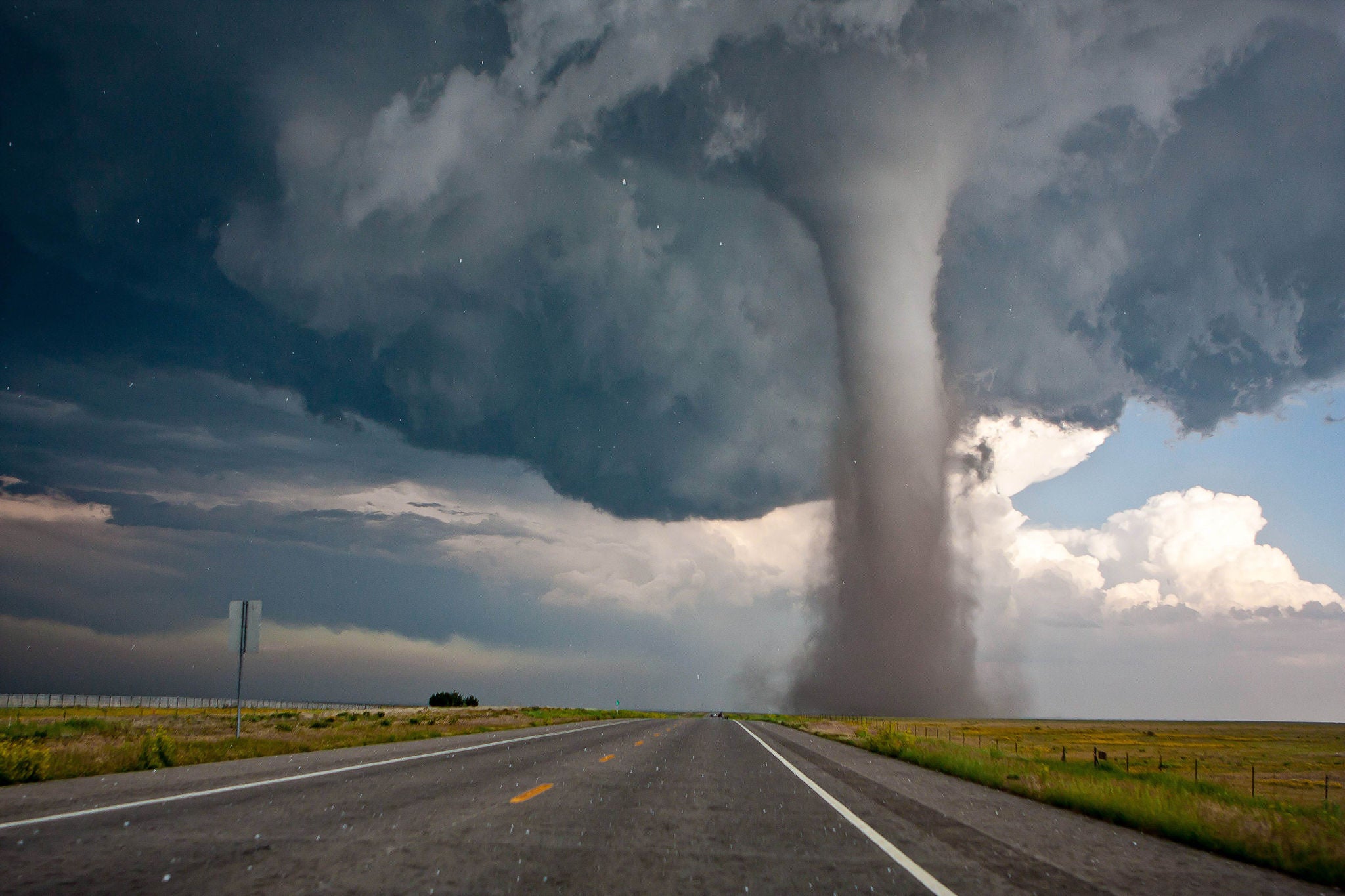 Landschaftsaufnahme von einem Tornado, der sich in der Nähe einer amerikanischen Strasse in unbebautem Gebiet bewegt