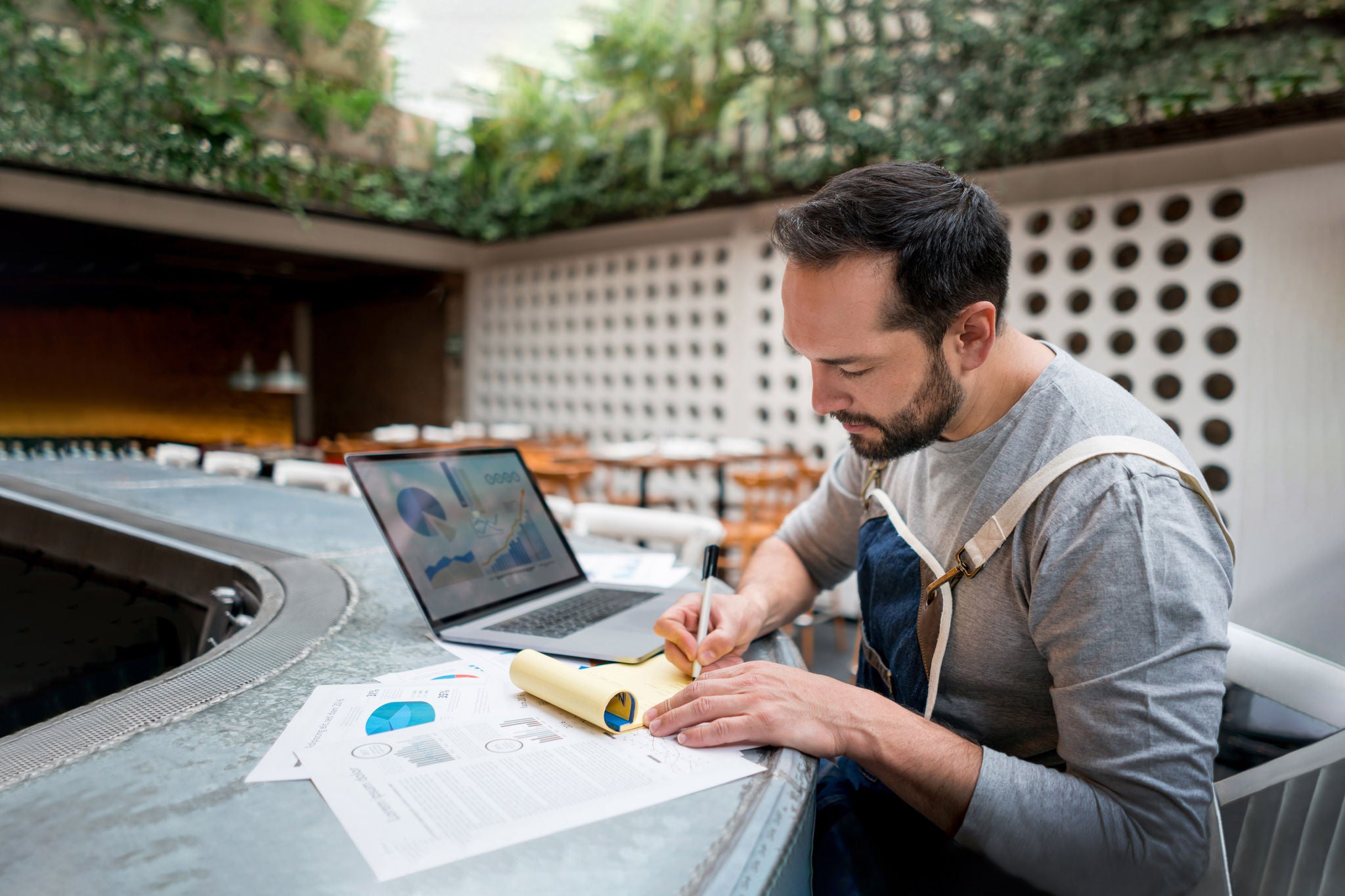 Portrait of a male business owner doing the books at a restaurant using a laptop computer. 