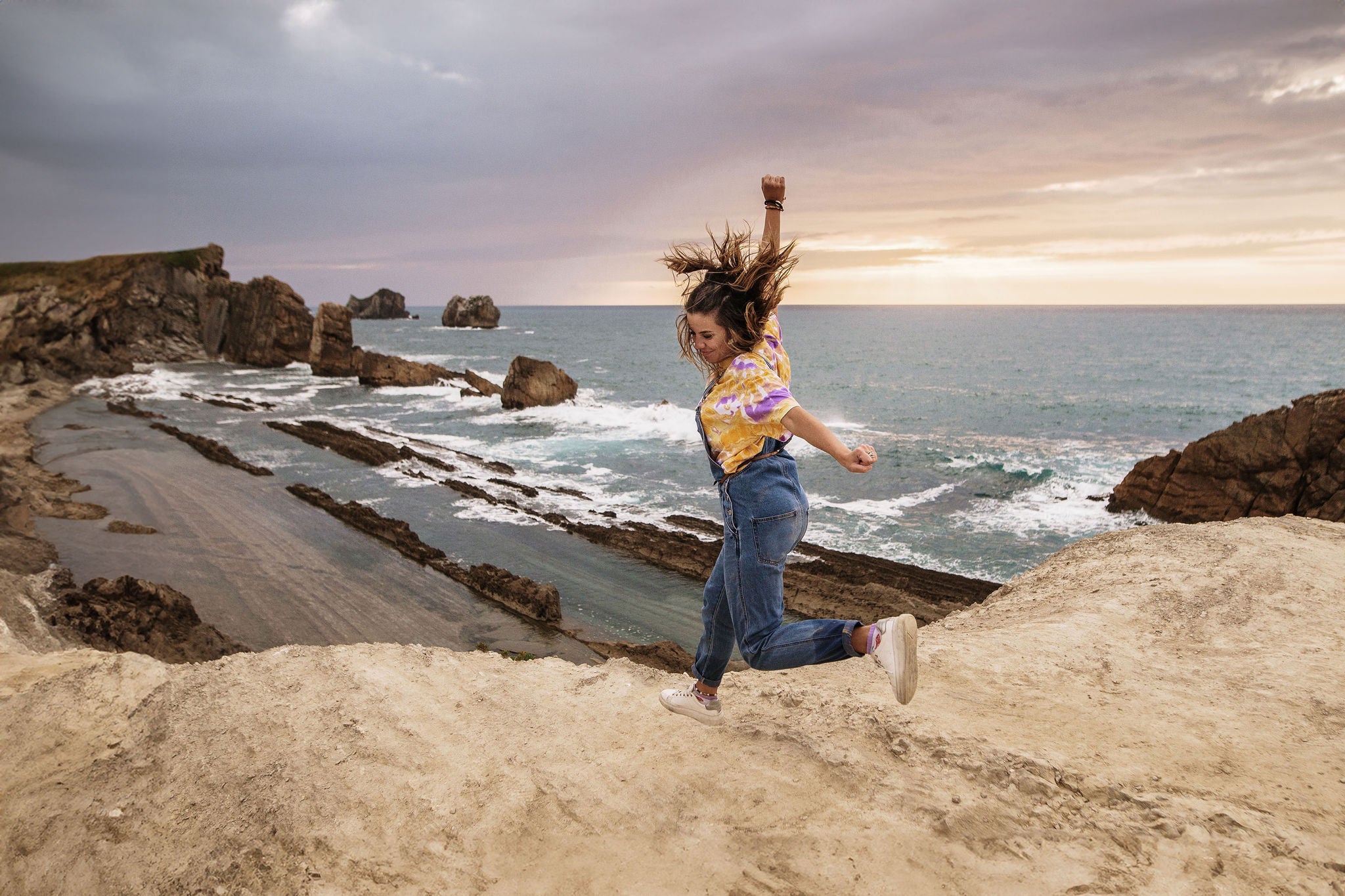 Young woman having fun jumping by the sea with a big smile