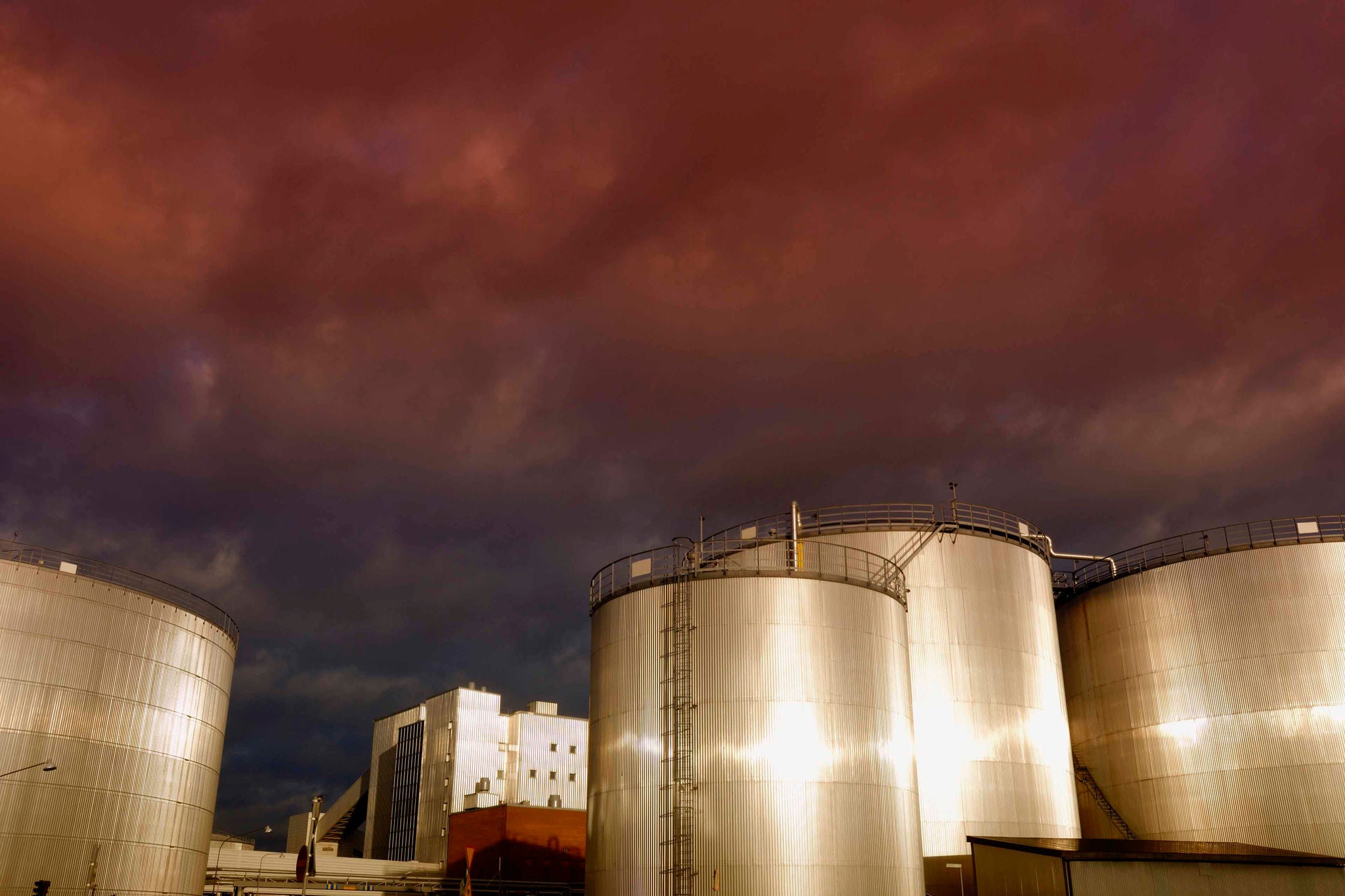 Oil and gas storage tanks at a red sunset