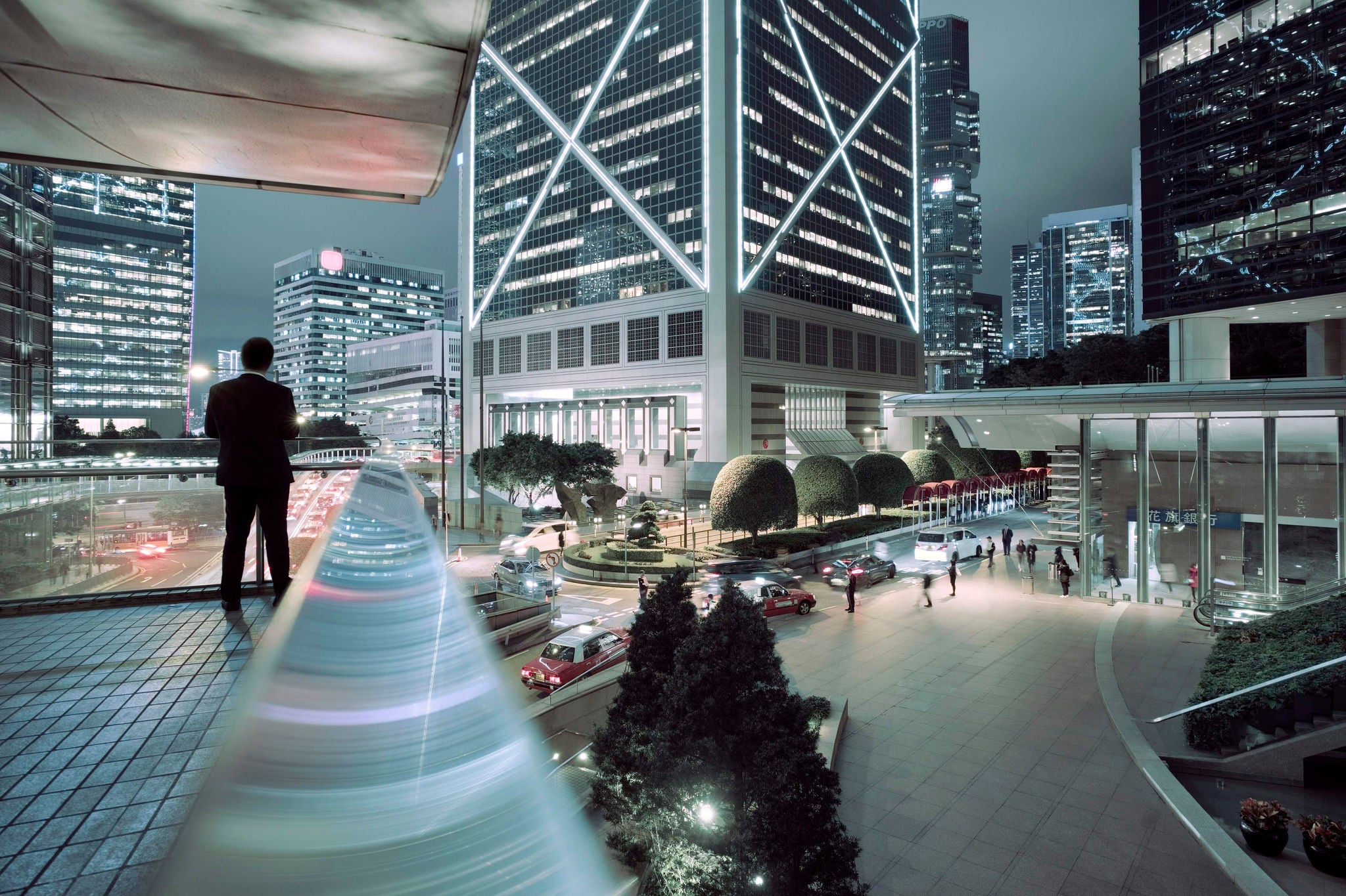 Overview of an illuminated Central (Business) District of Hong Kong with businessman enjoying the view.