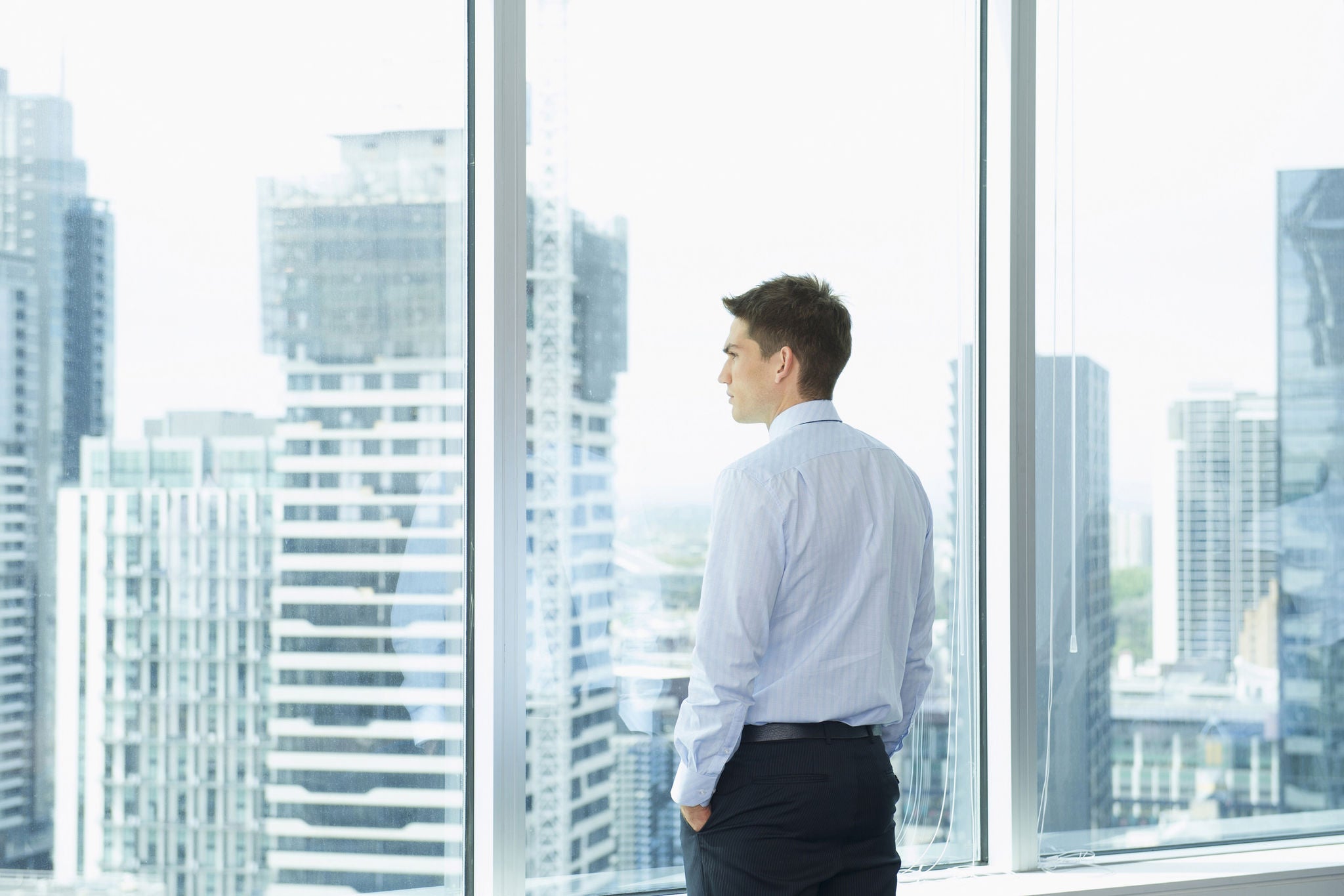 Businessman looking cityscape office window