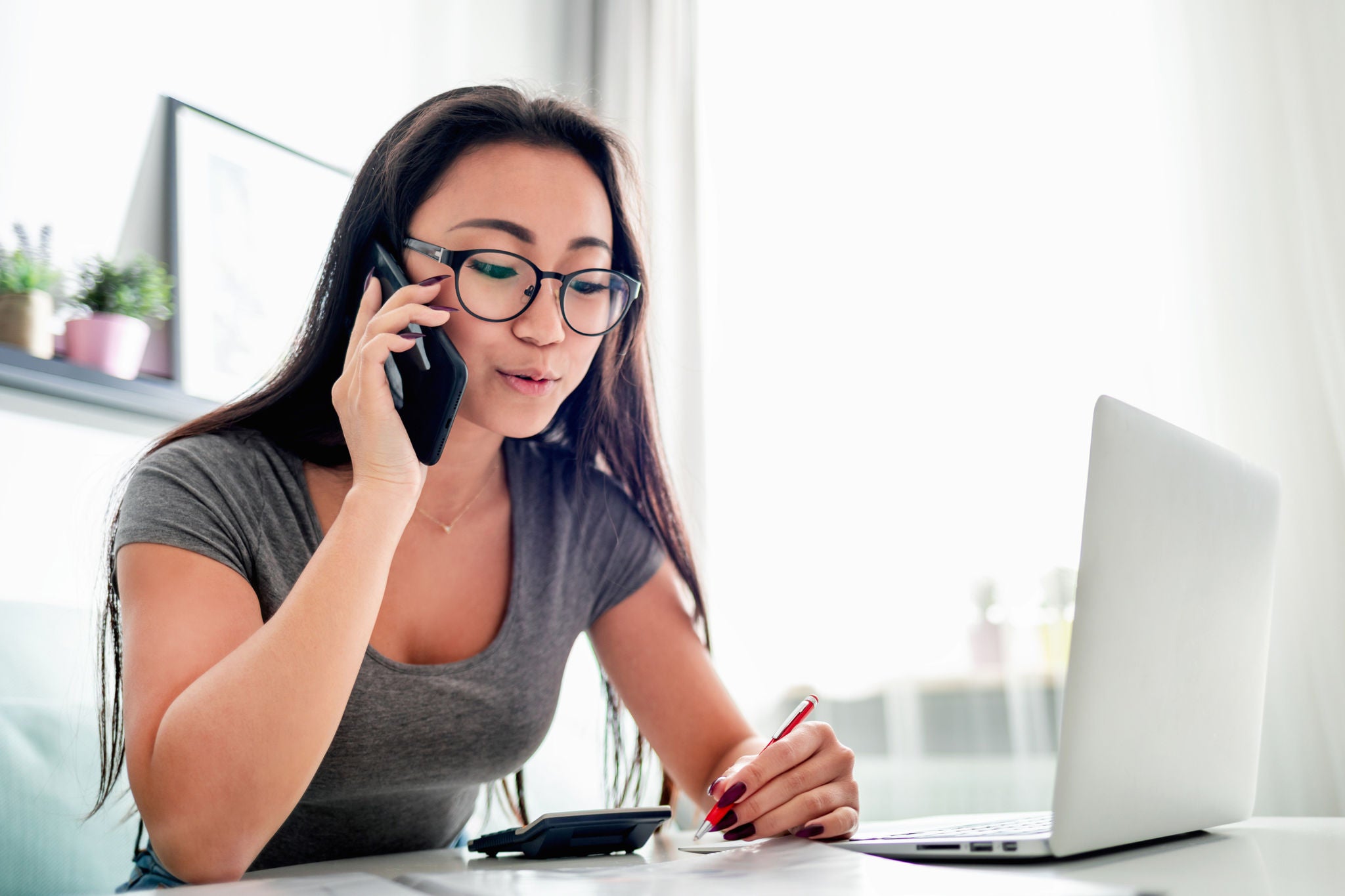 Woman talking on the phone sitting in front of a laptop