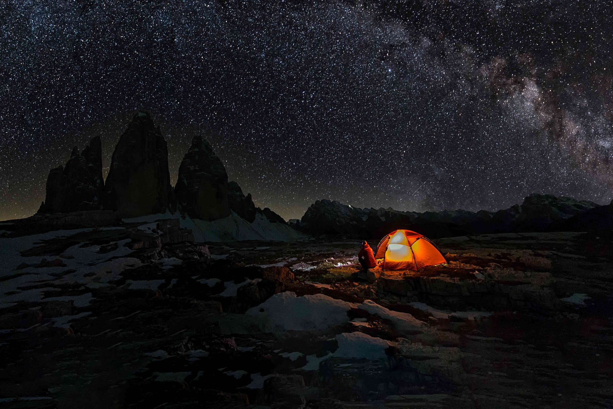 Lonely Camper in front of illuminated tent in Dolomites under Milky Way at Tre Cime of the Dolomites (Drei Zinnen)