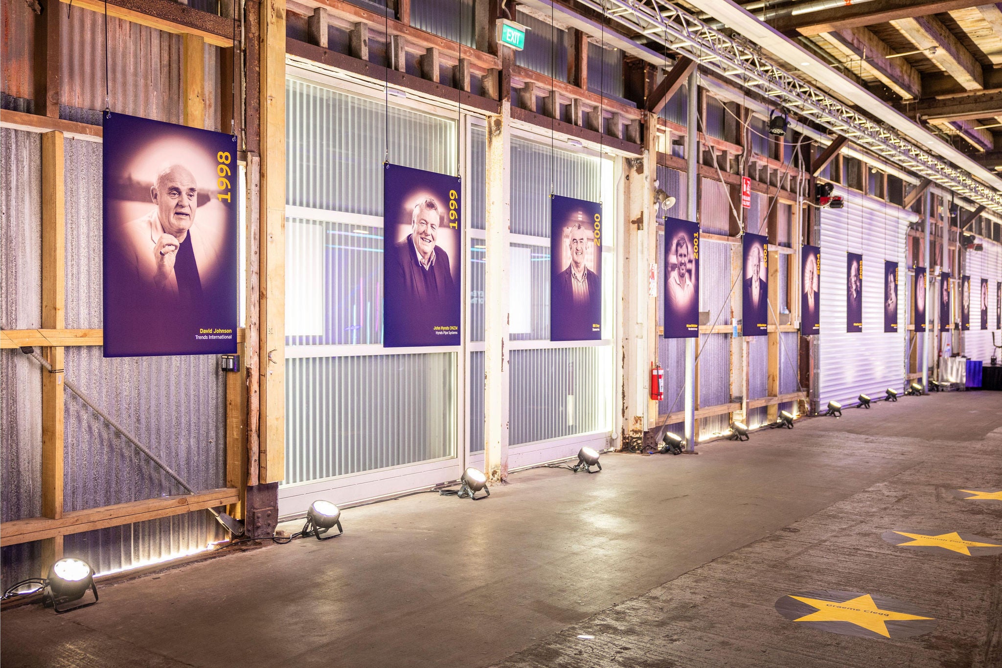 An industrial-style hallway with a series of framed portraits on the wall