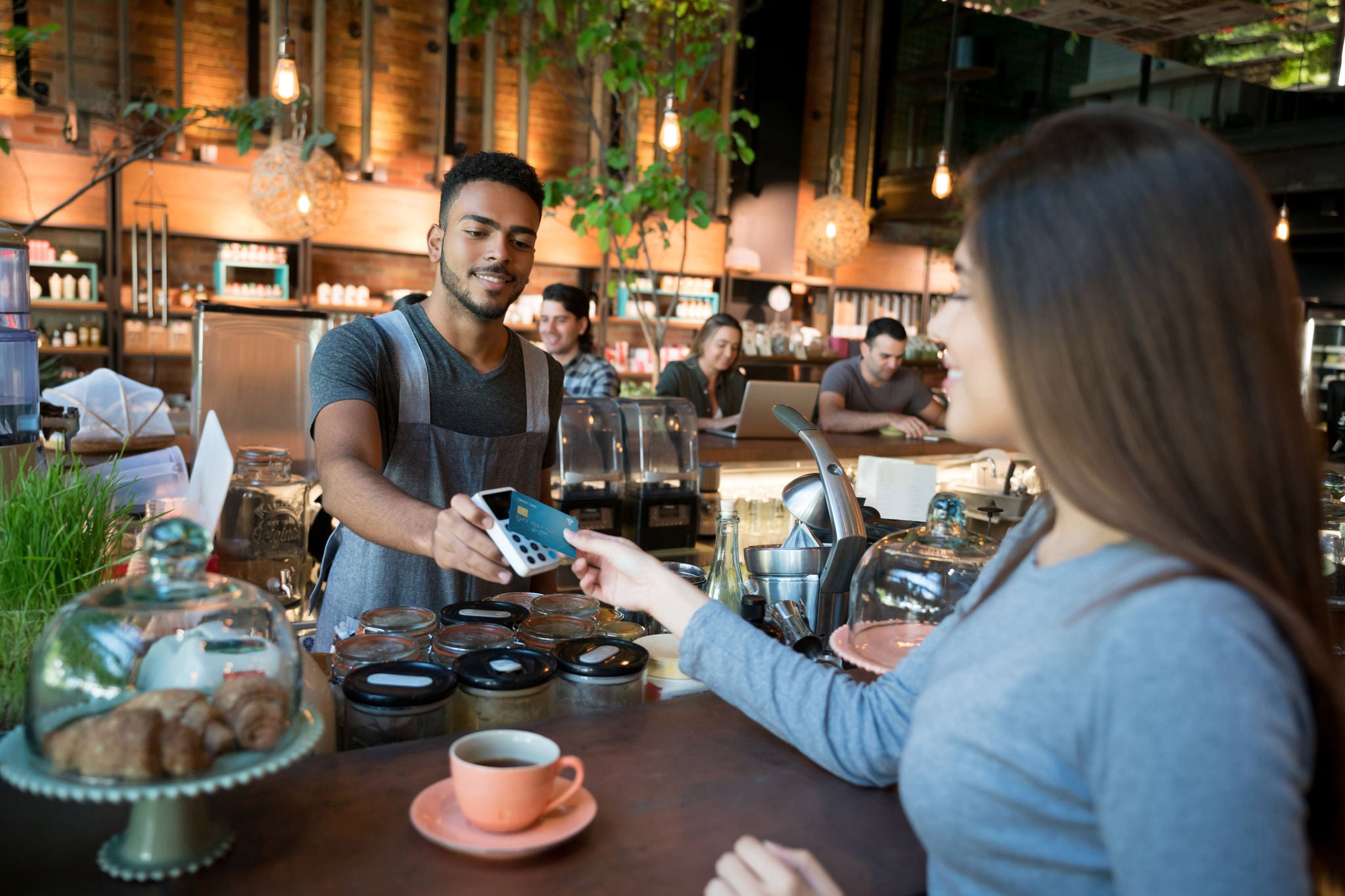 Happy woman making a contactless payment at a restaurant with a credit card - food service concepts.