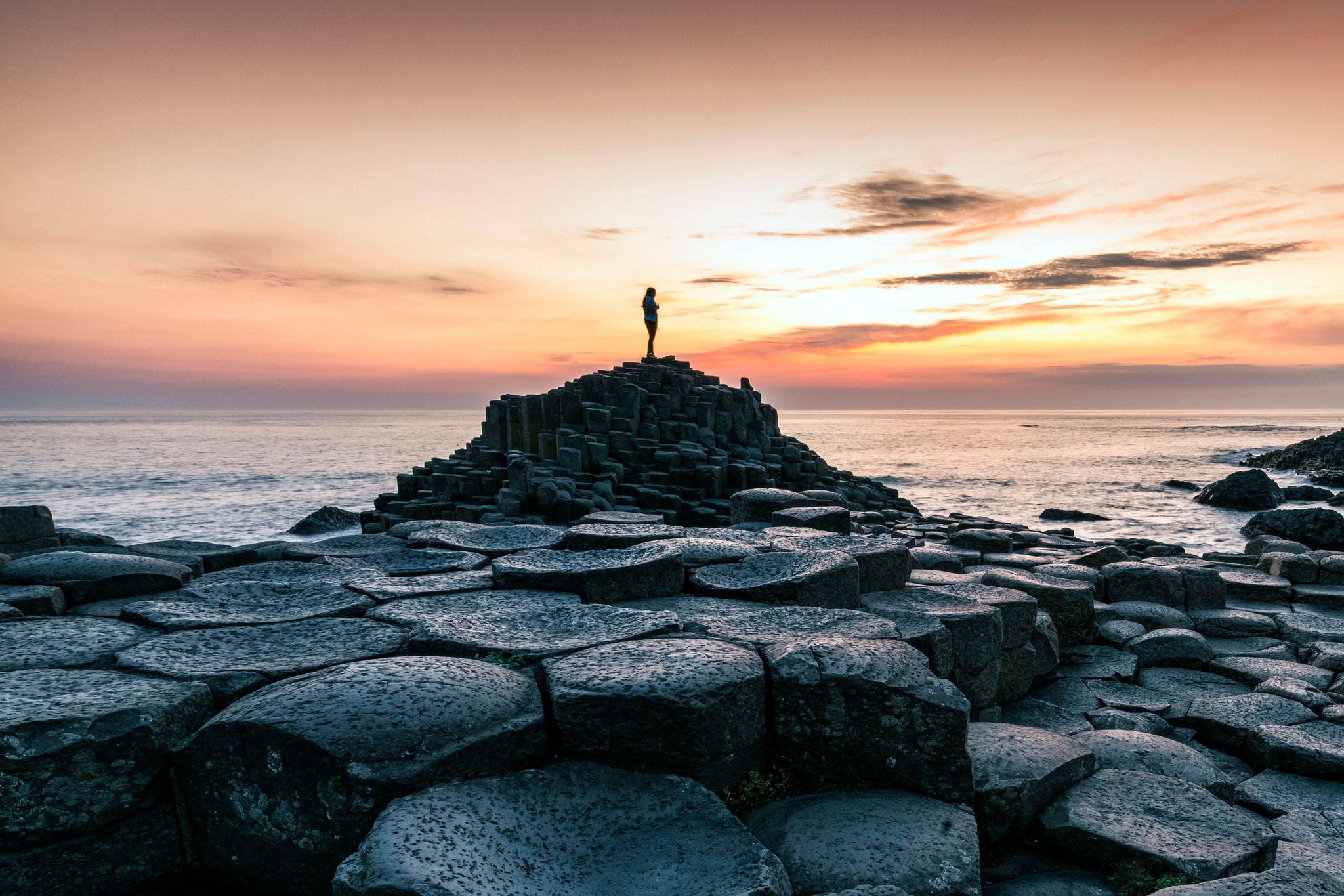 United Kingdom, Northern Ireland, County Antrim: silhouette of a person at the Giants causeway at sunset.