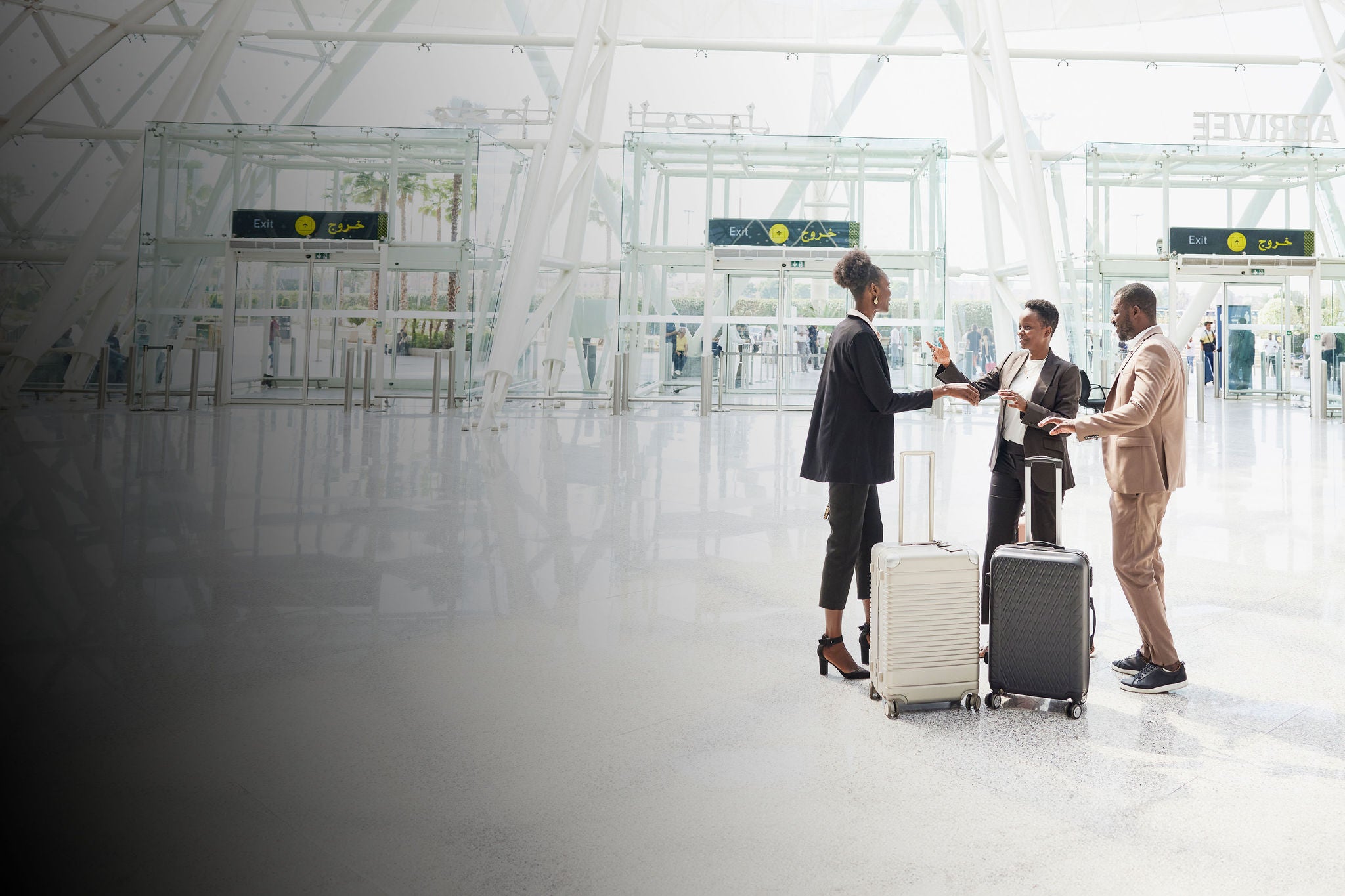 Wide shot of business colleagues in greeting each other in airport arrivals terminal after flight