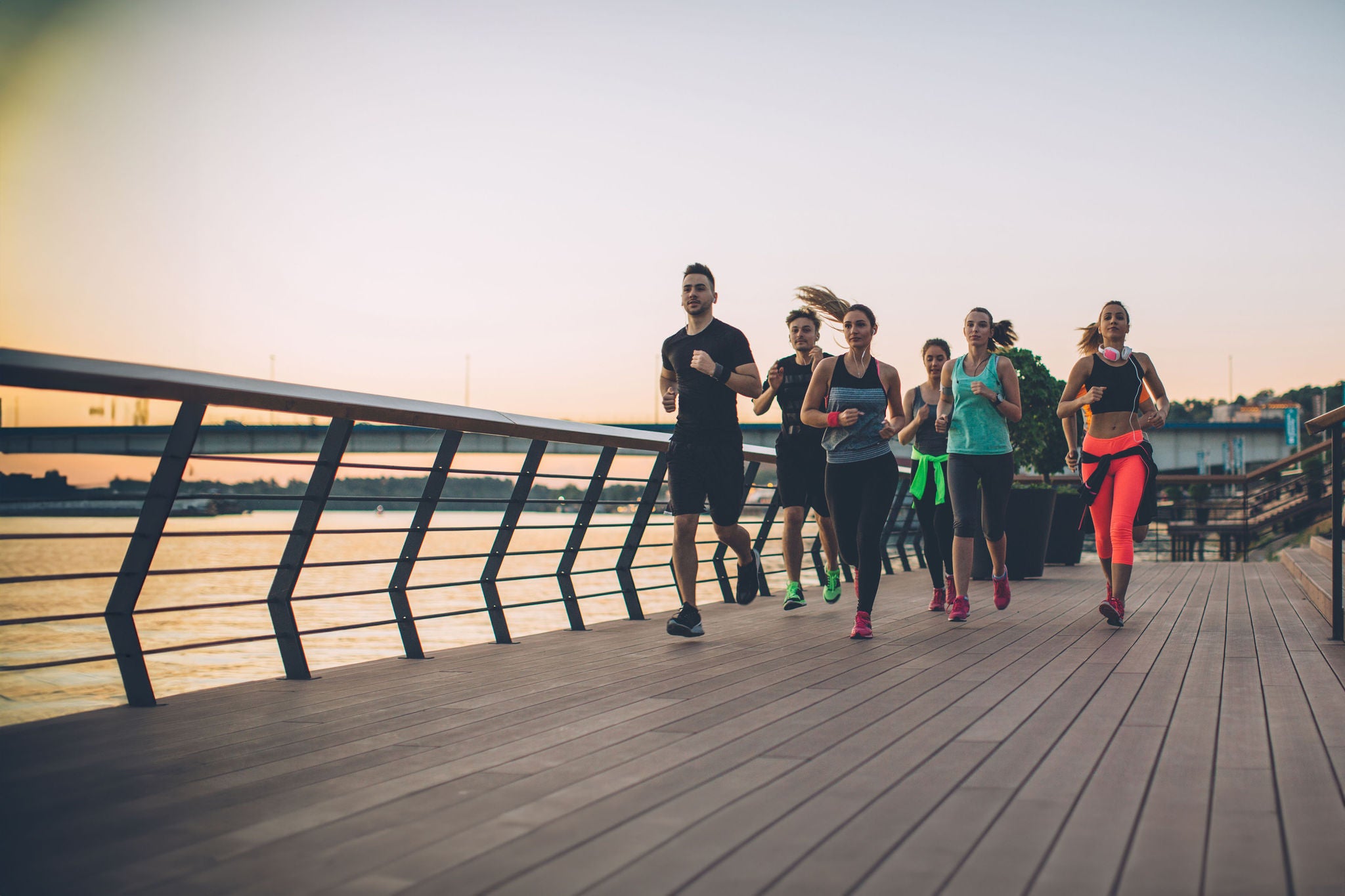 Young men and women running in city by river