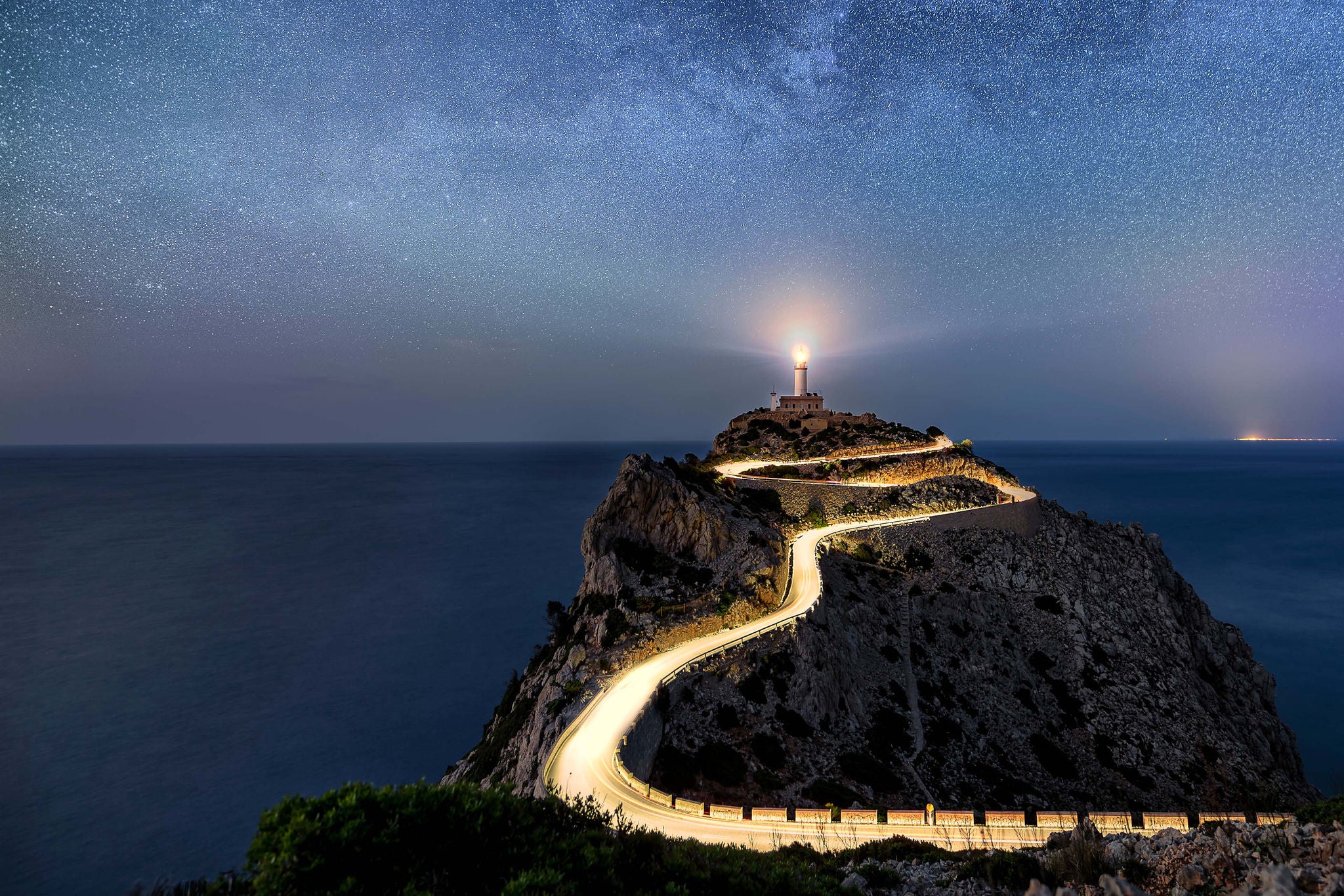 Night time with stars and illuminated road at the Far de Formentor lighthouse