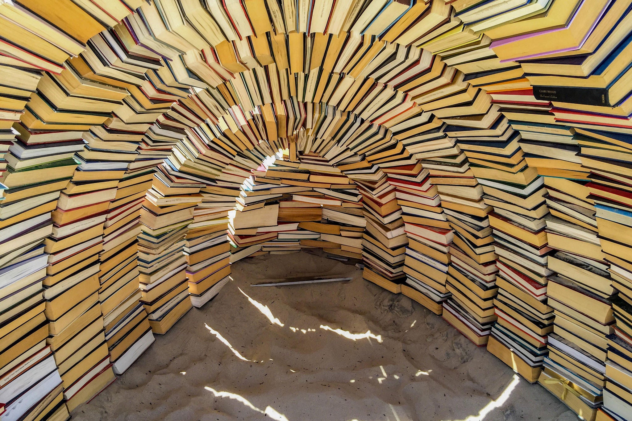 An art installation cave made of books on a beach