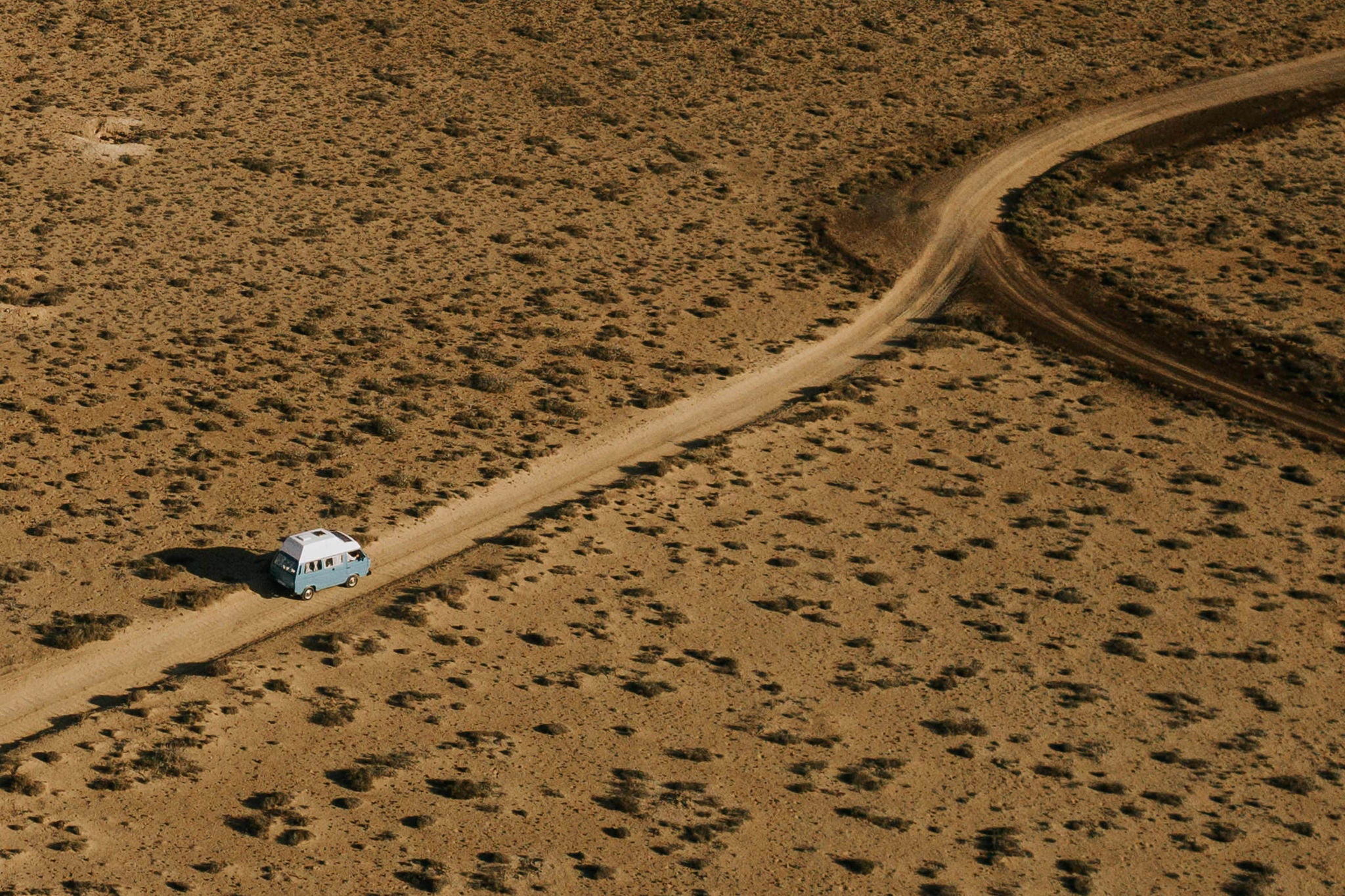 Spectacular drone view of automobile riding along off road in highland terrain in sunny evening