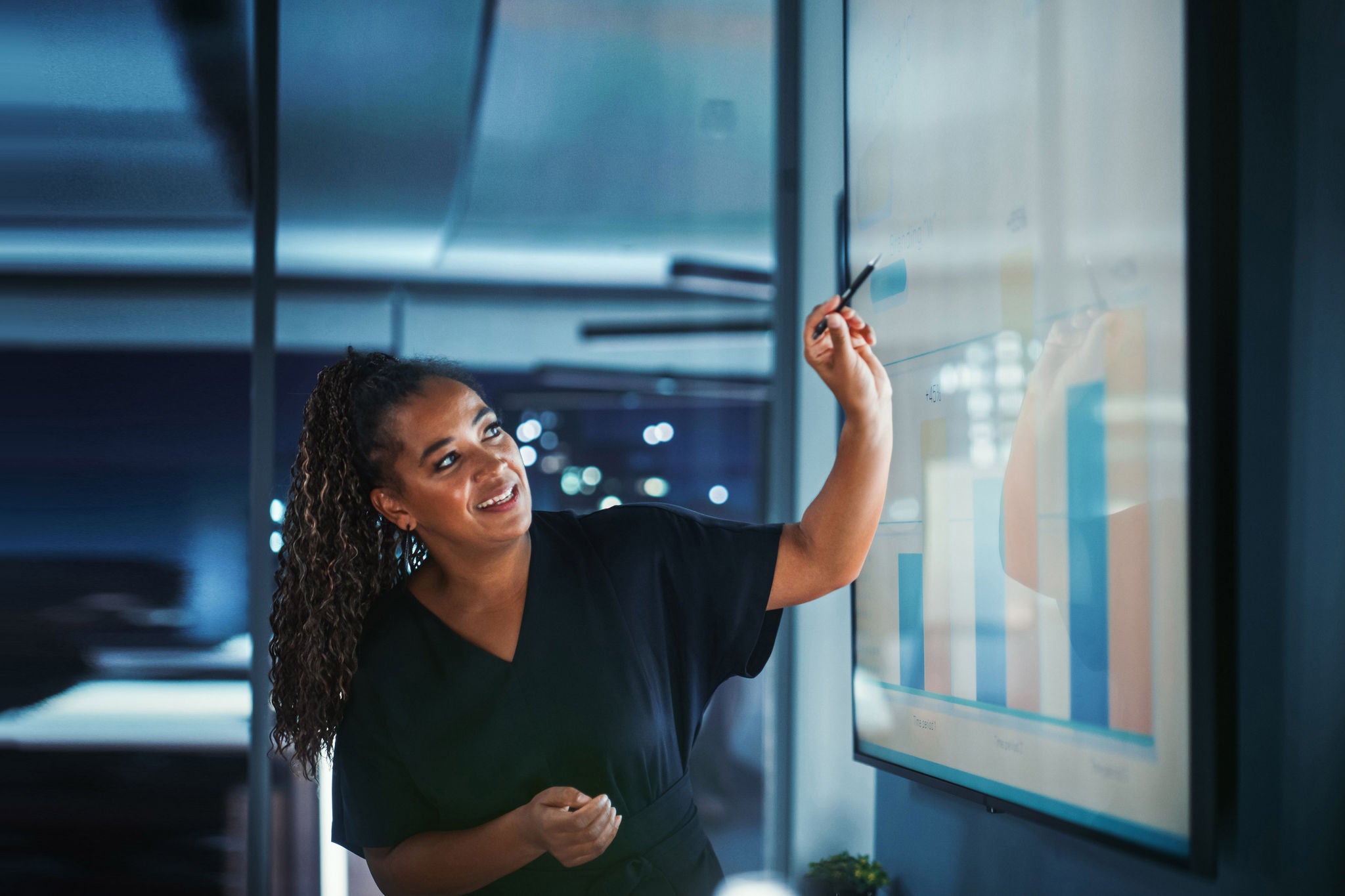 Company Operations Director Holds Sales Meeting Presentation for Employees and Executives. Creative Black Female Uses TV Screen with Growth Analysis; Charts; Ad Revenue. Work in Business Office.