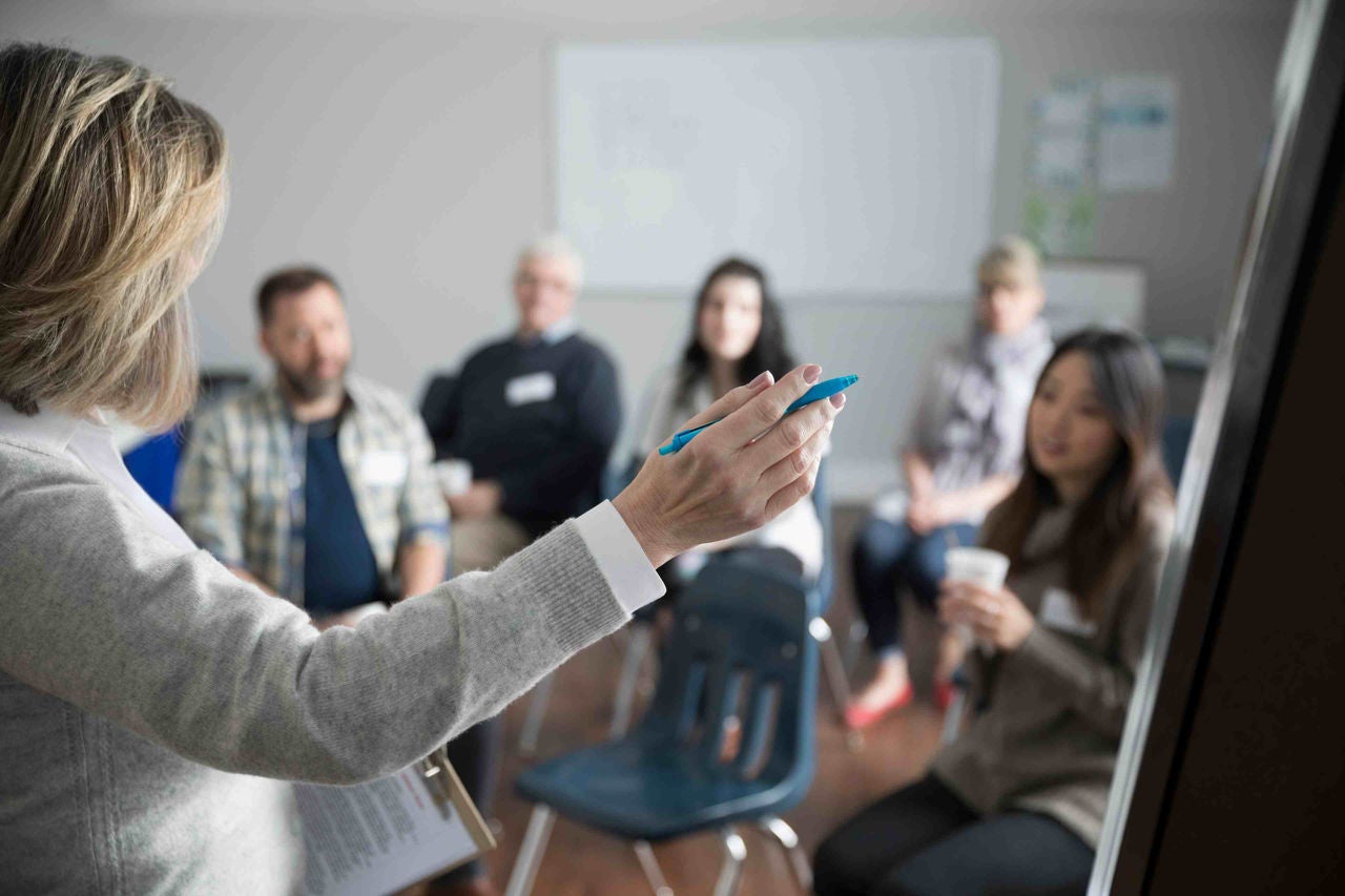 Woman At Whiteboard Leading Support Group In Community Center