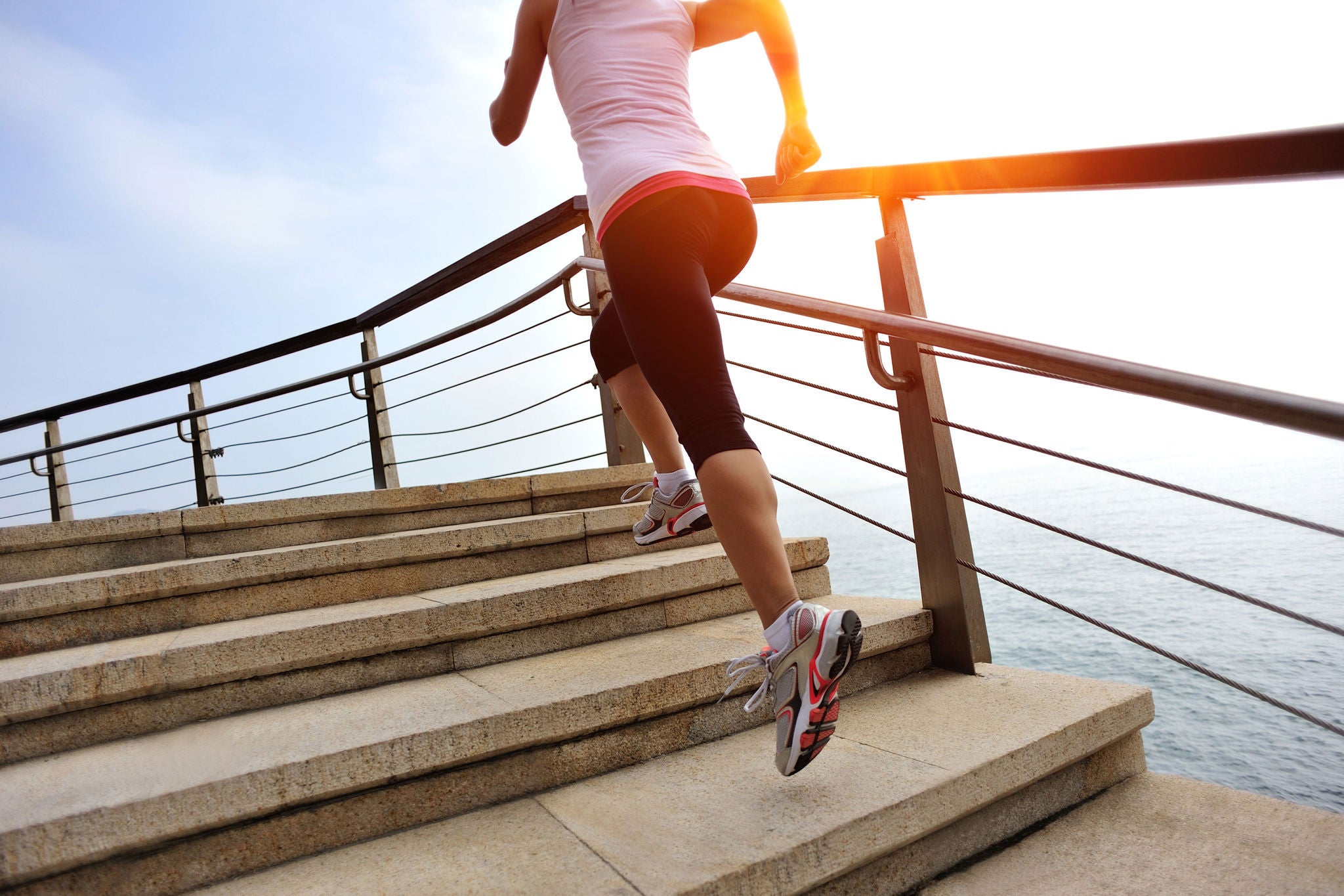 fitness woman running at stone stairs to mountain peak