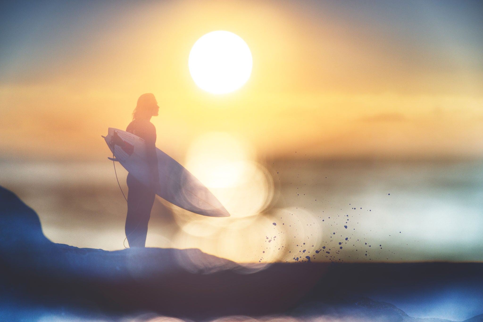 A surfer silhouetted against a setting sun.