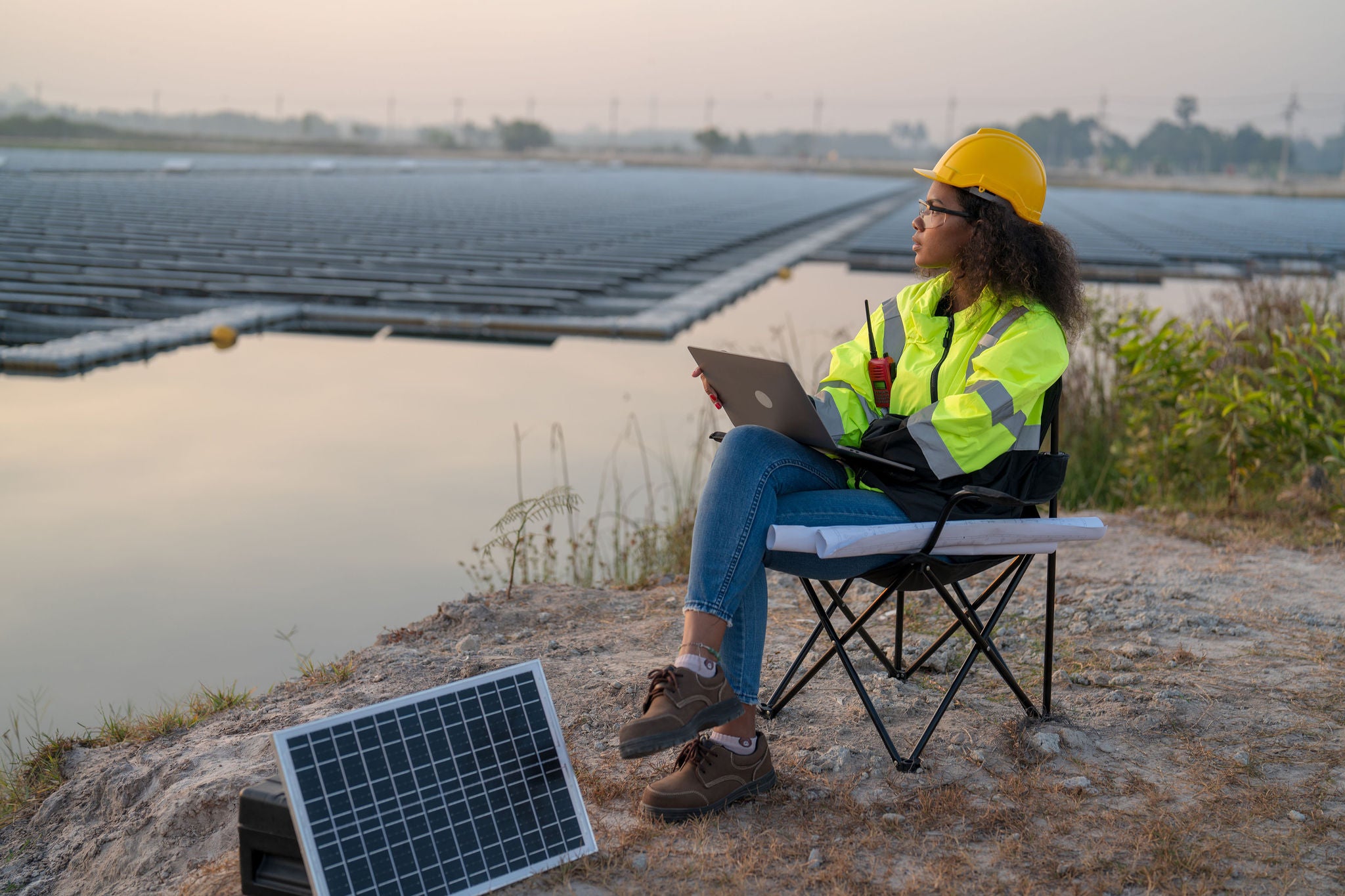 Black female engineer wearing green safety jacket working at floating solar farm