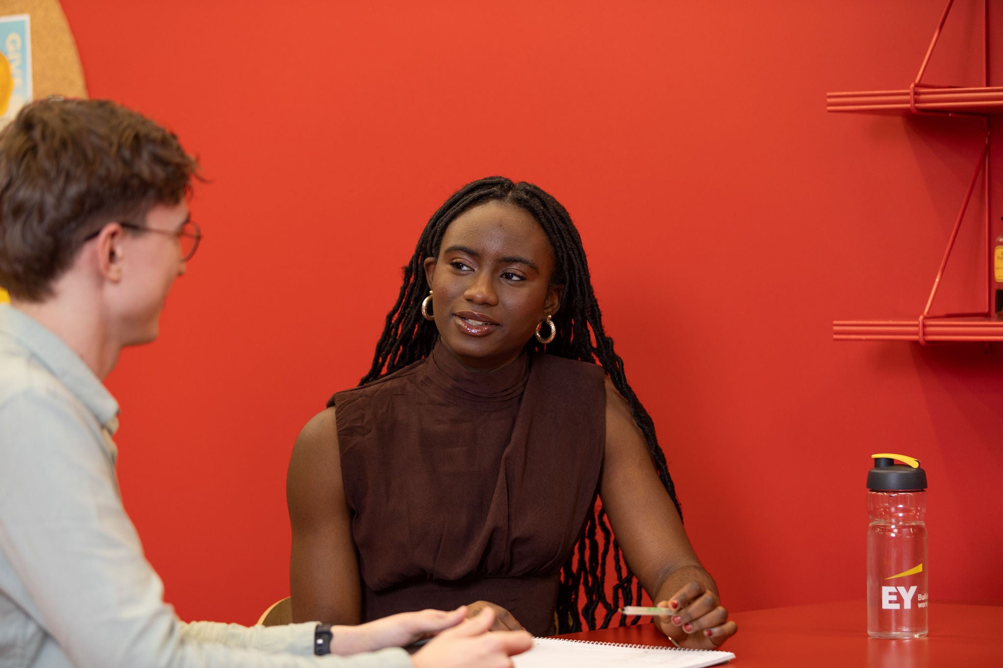 Two students are sitting at the desk and discussing.