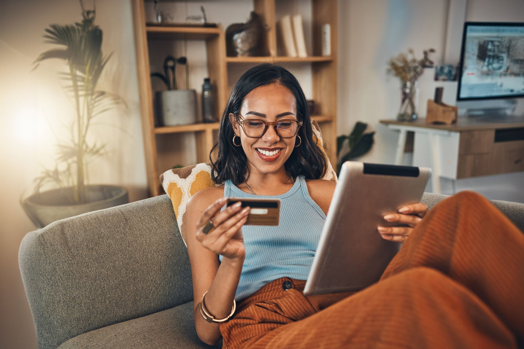 Ecommerce, credit card and woman on a couch, tablet or payment with an order, home or online shopping. Female person, girl or customer on a sofa, technology or buying products with retail or banking.