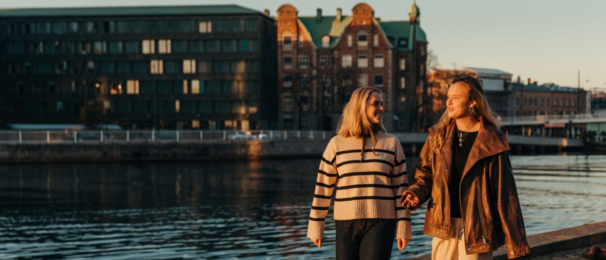 Two women walking and talking along the side of a river