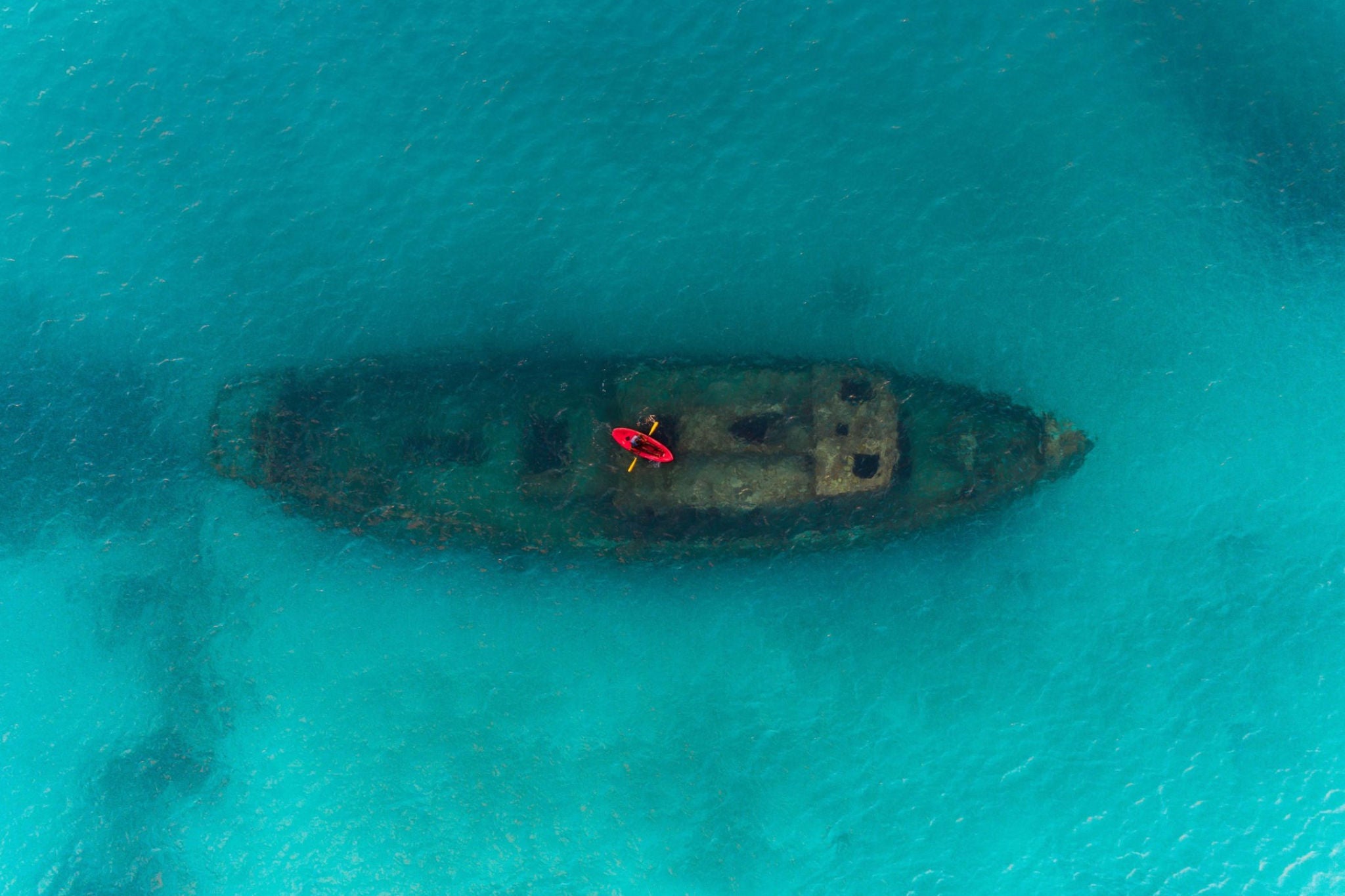 EY red kayak floating above a shipwreck carlisle bay barbados background