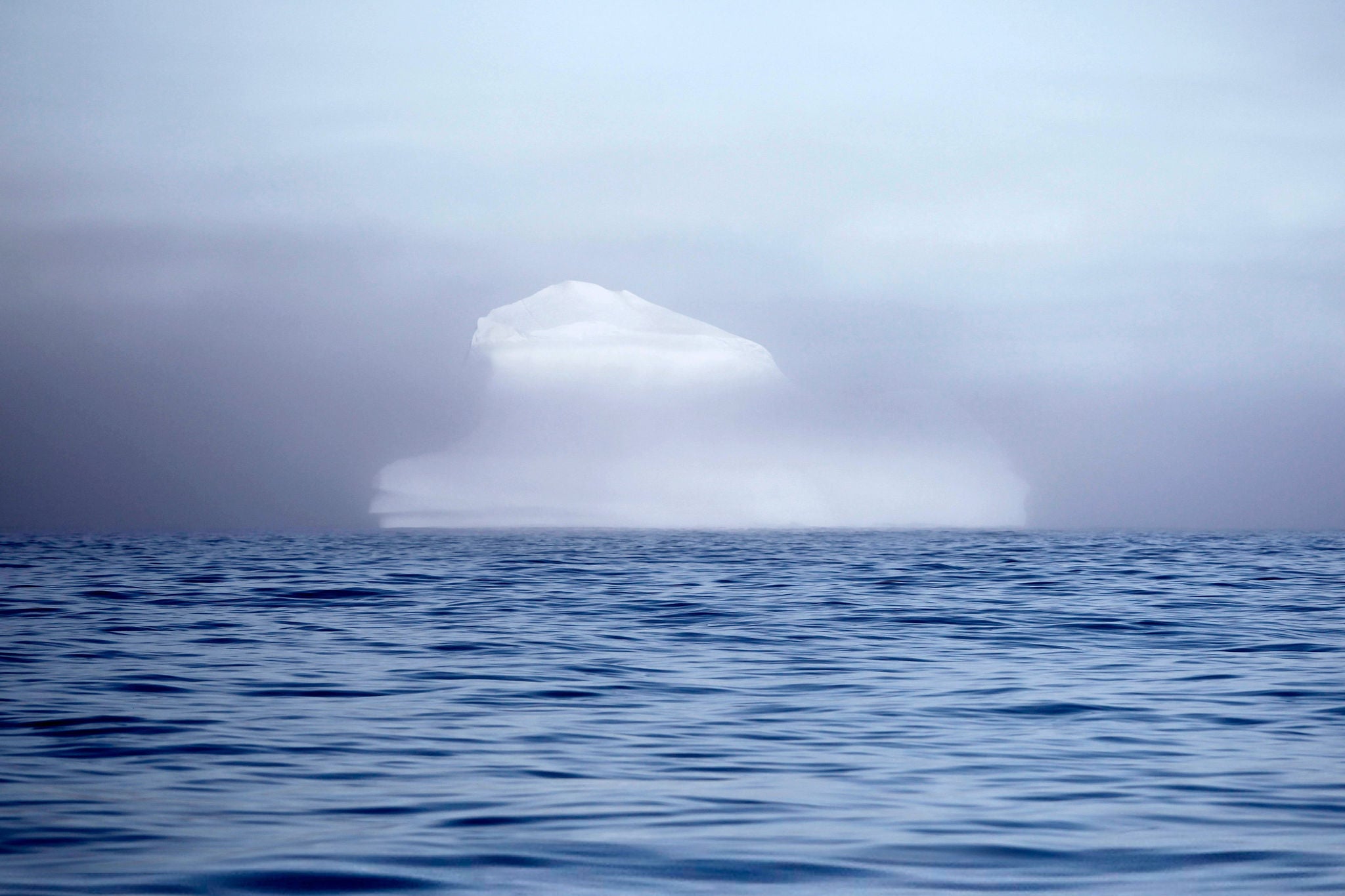 Ein Eisberg schwimmt durch Nebel halb verdeckt im Polarmeer