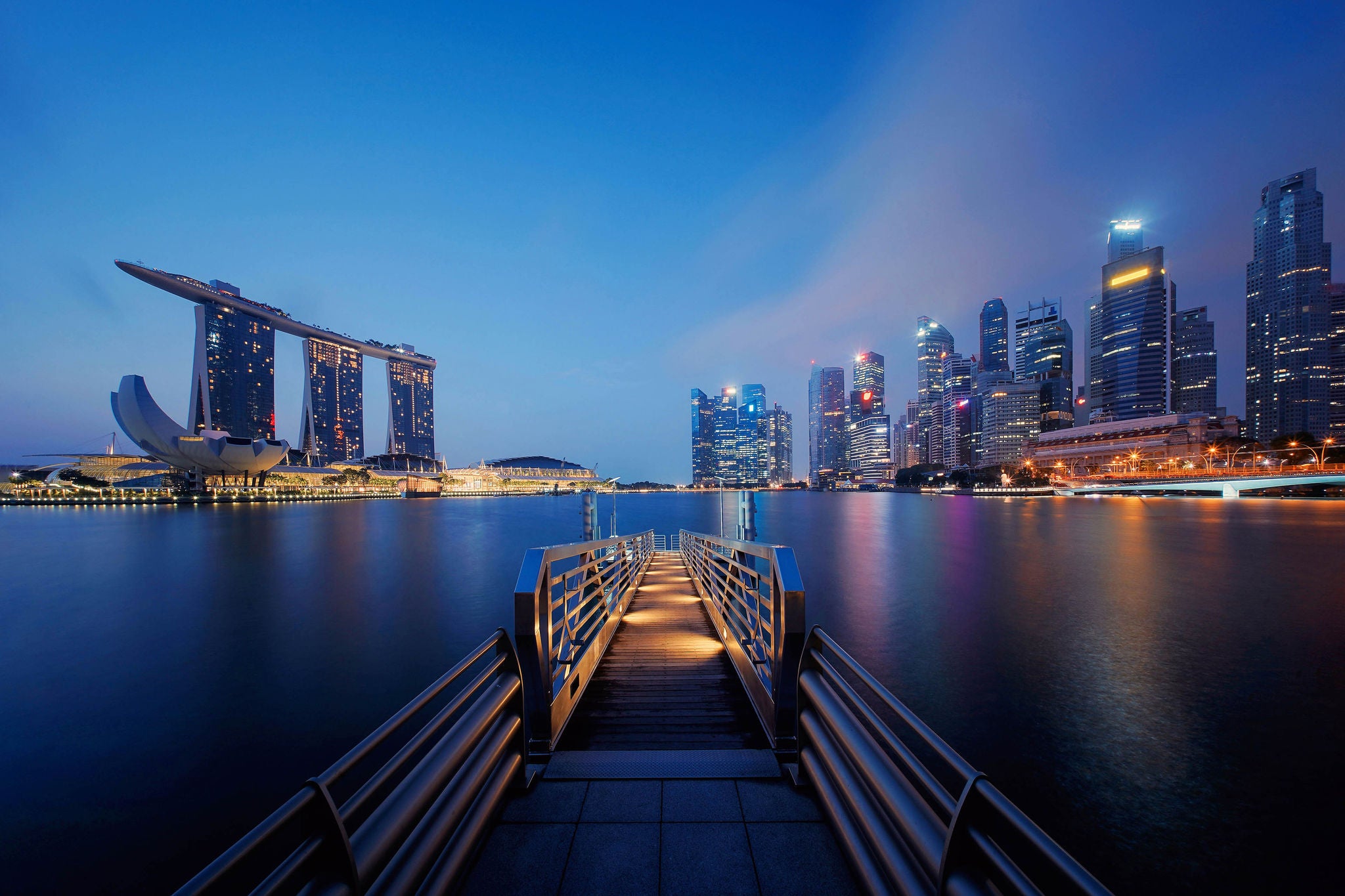 BRIDGE OVER RIVER BY ILLUMINATED BUILDINGS AGAINST SKY