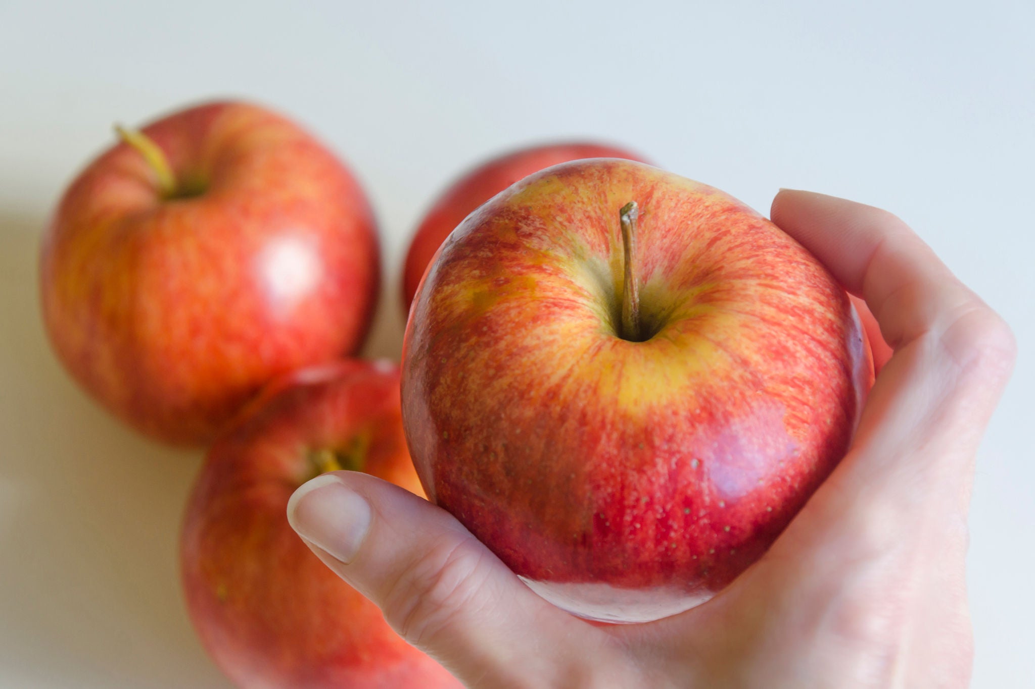 Woman holding one Red Apple among other Red apples on the background