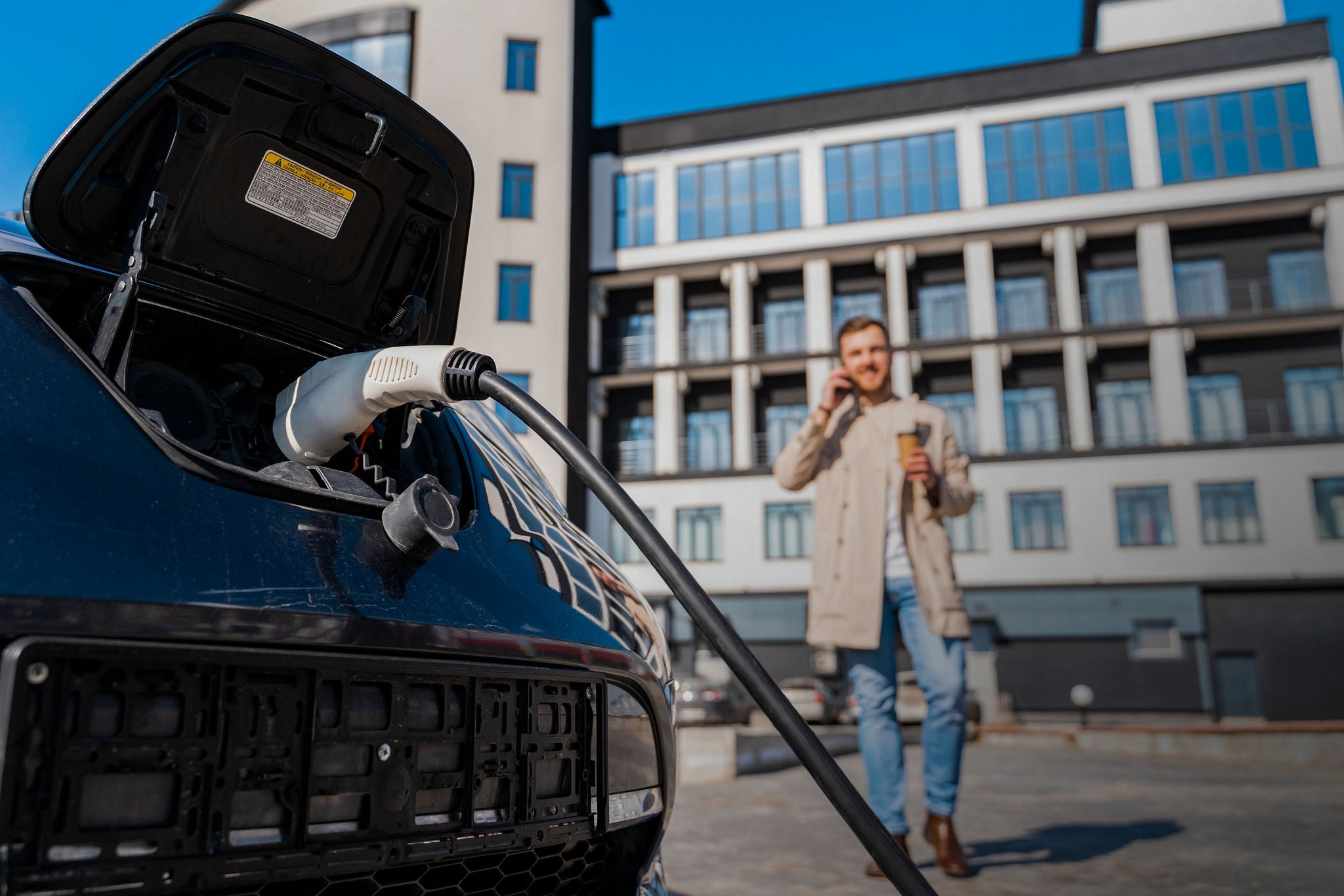 Man talks on the phone while his car is charging