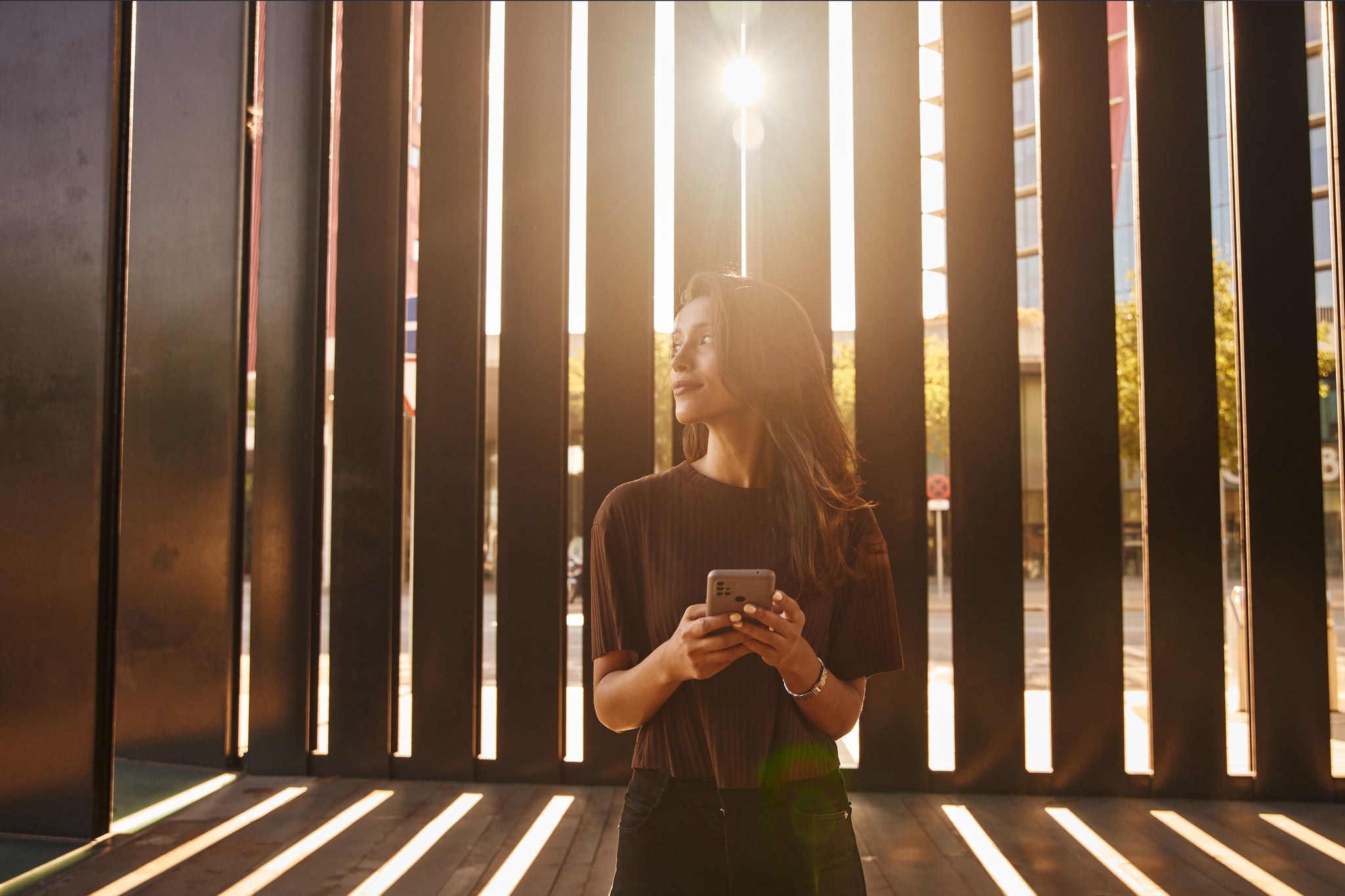 Businesswoman standing in sun holding mobile phone