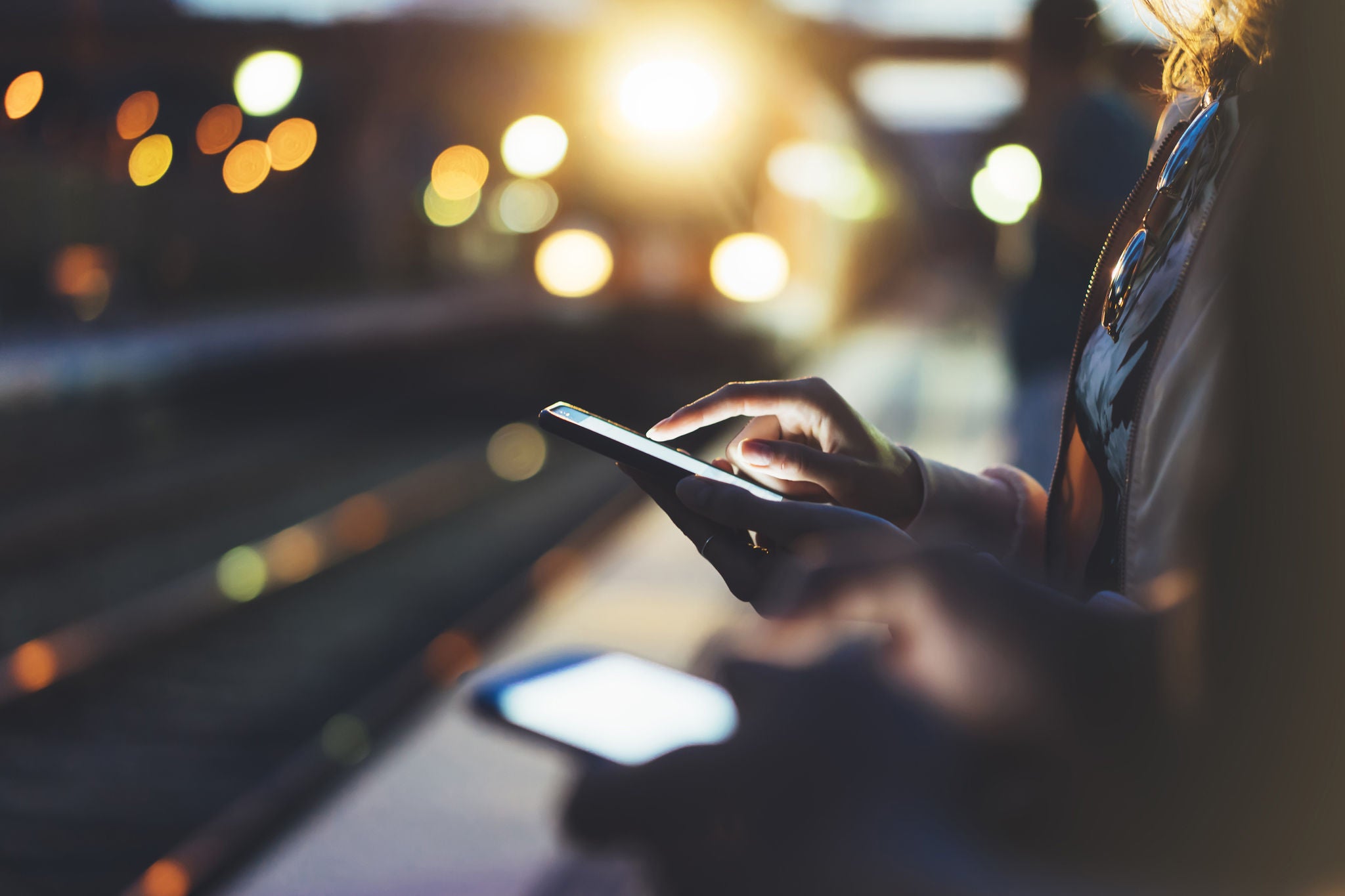 woman waiting on station platform using phone