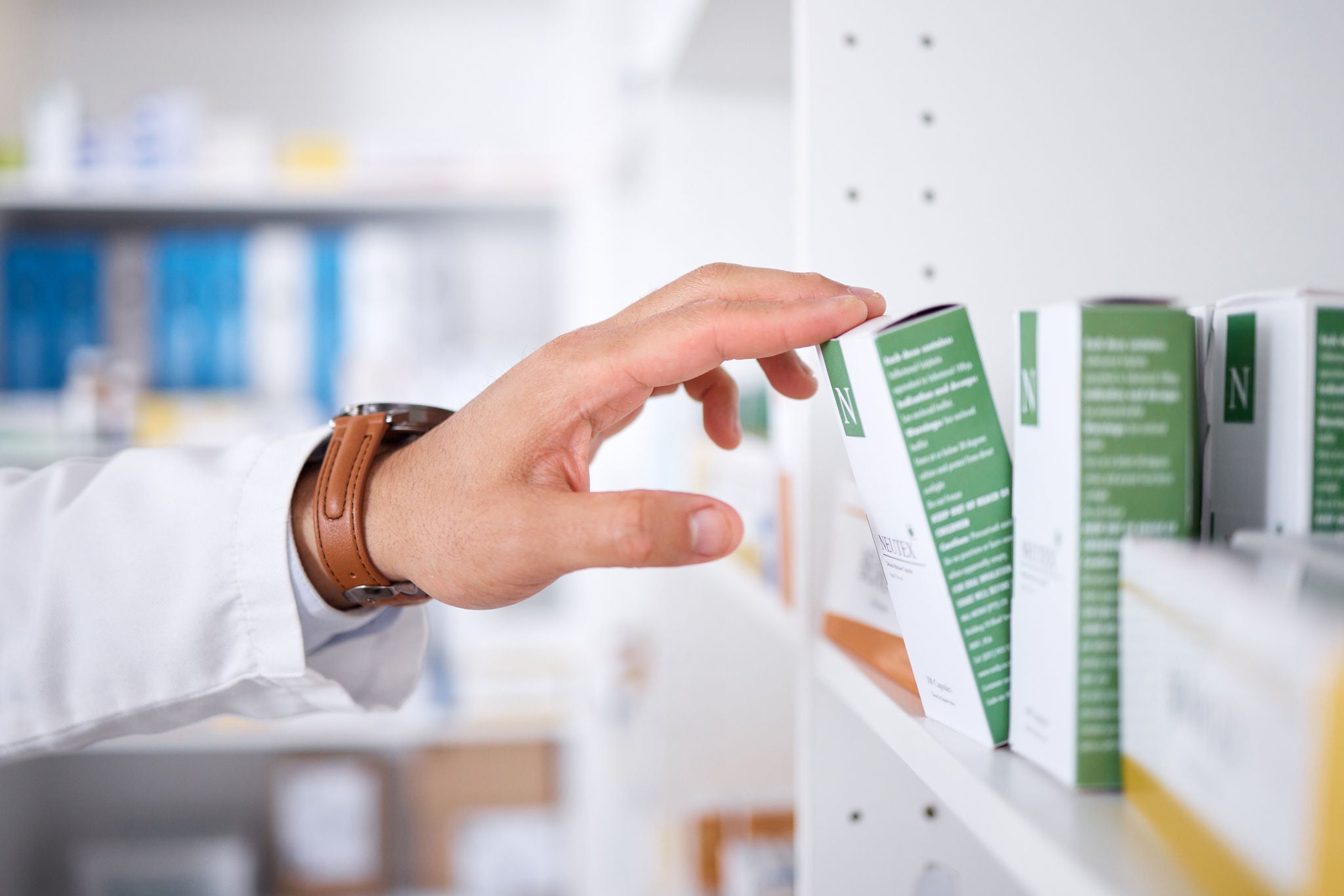 Pharmacist hand, shelf and boxes with choice, packing stock and inventory inspection in shop. Pharmacy manager, package and product label for healthcare, pills and health with drugs in retail store