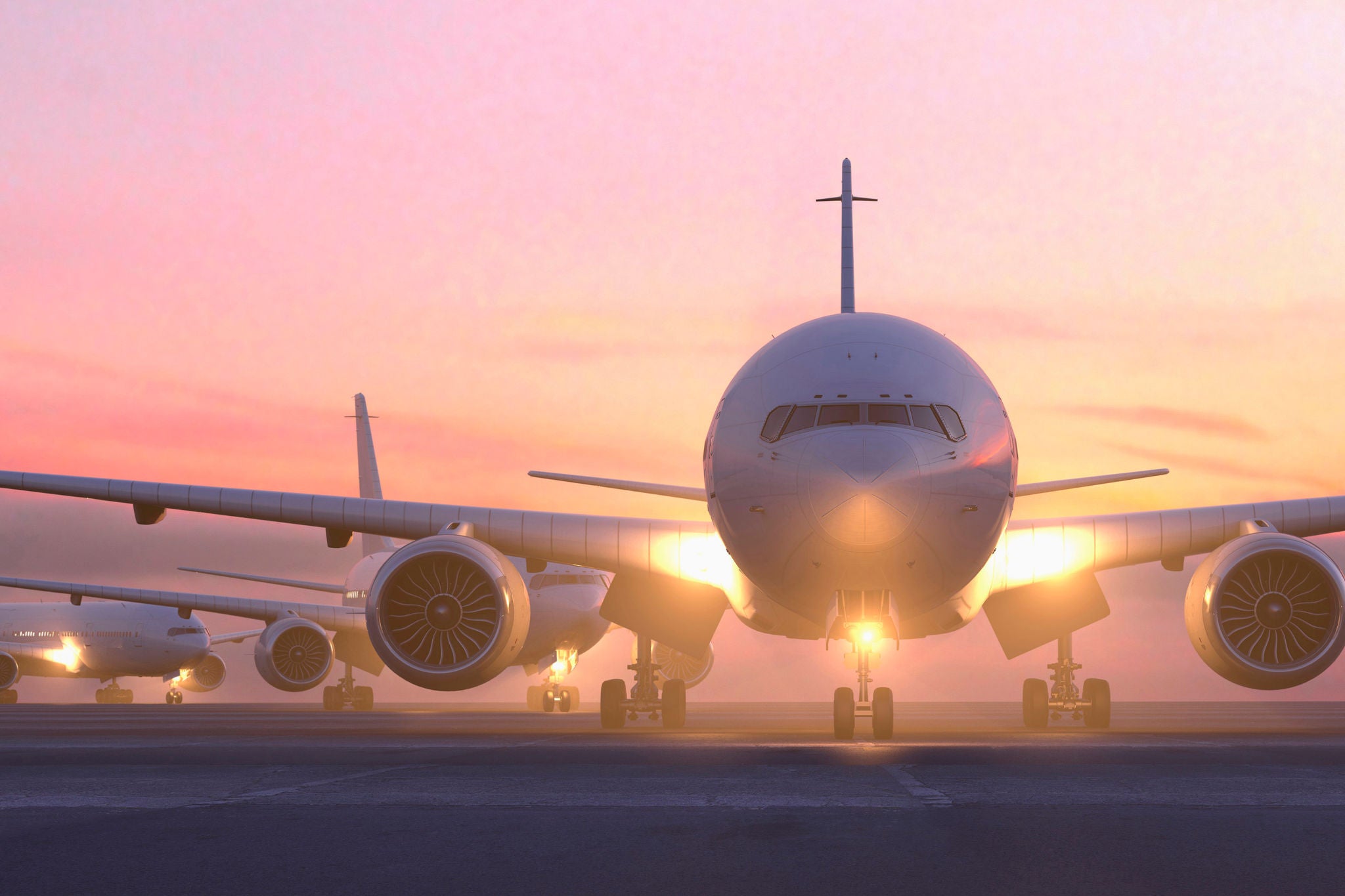 Airplanes taxiing on runway at sunset