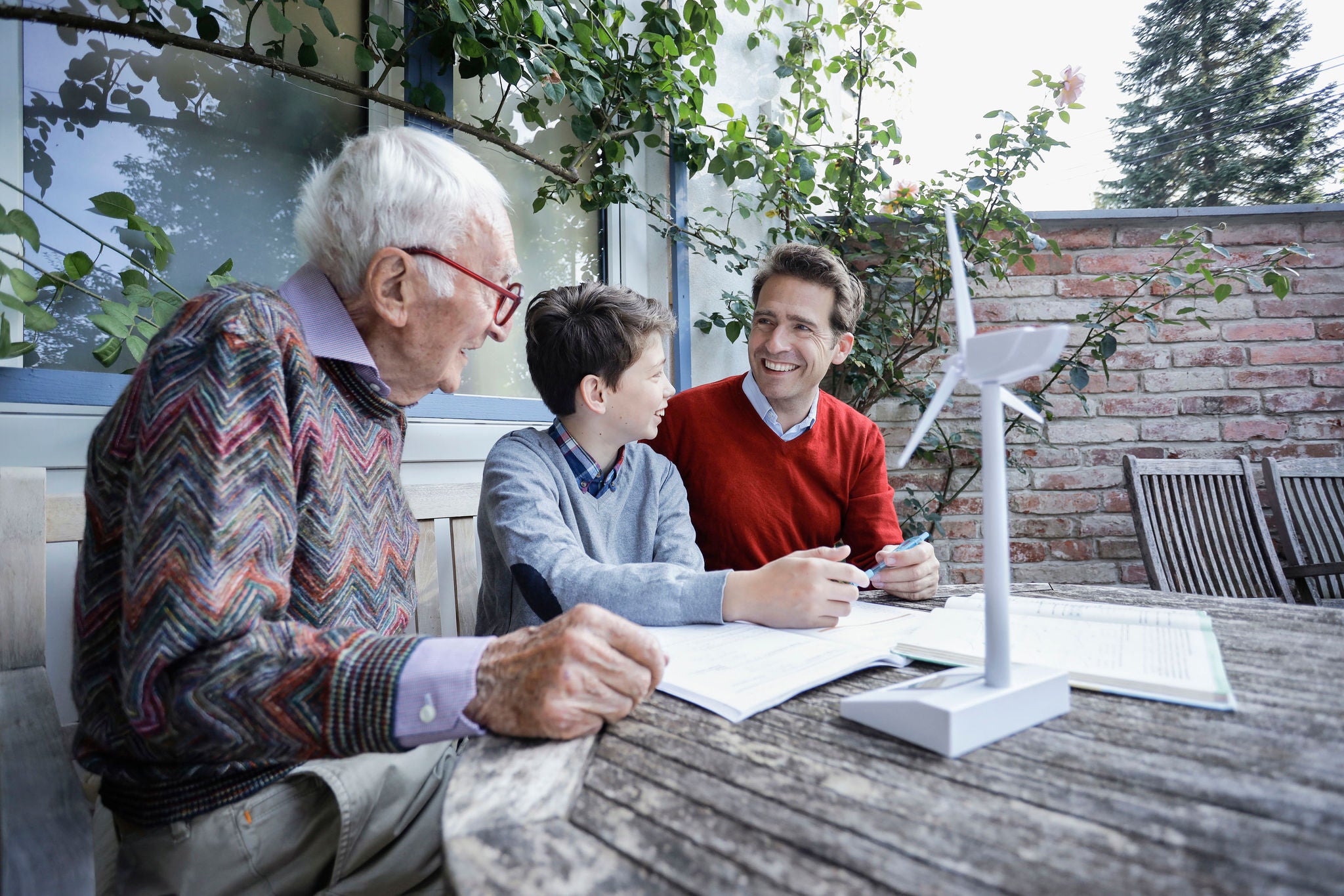 Tre generationer sidder ved havebord og hygger sig