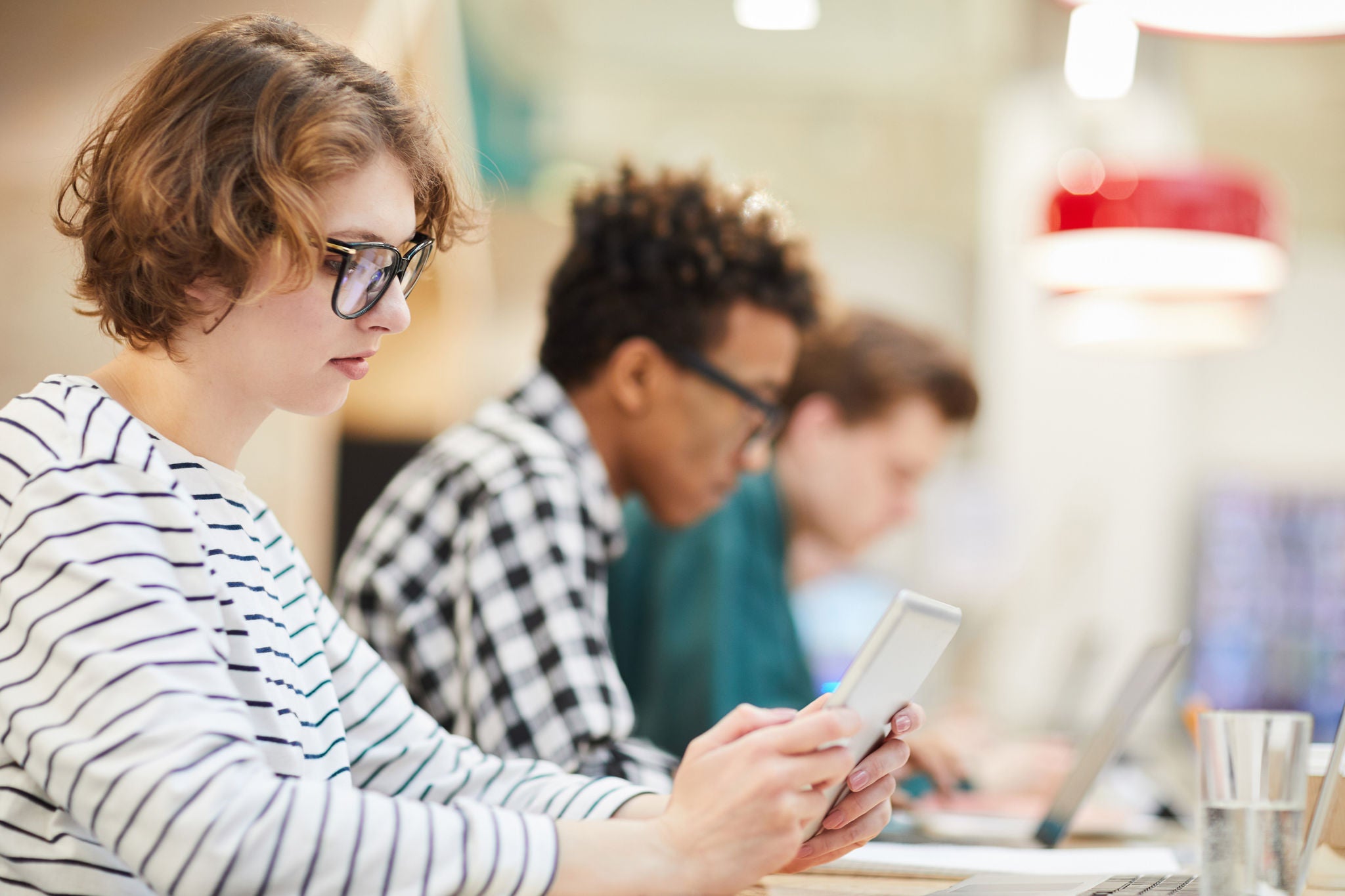 Serious thoughtful student girl in glasses sitting at table in university