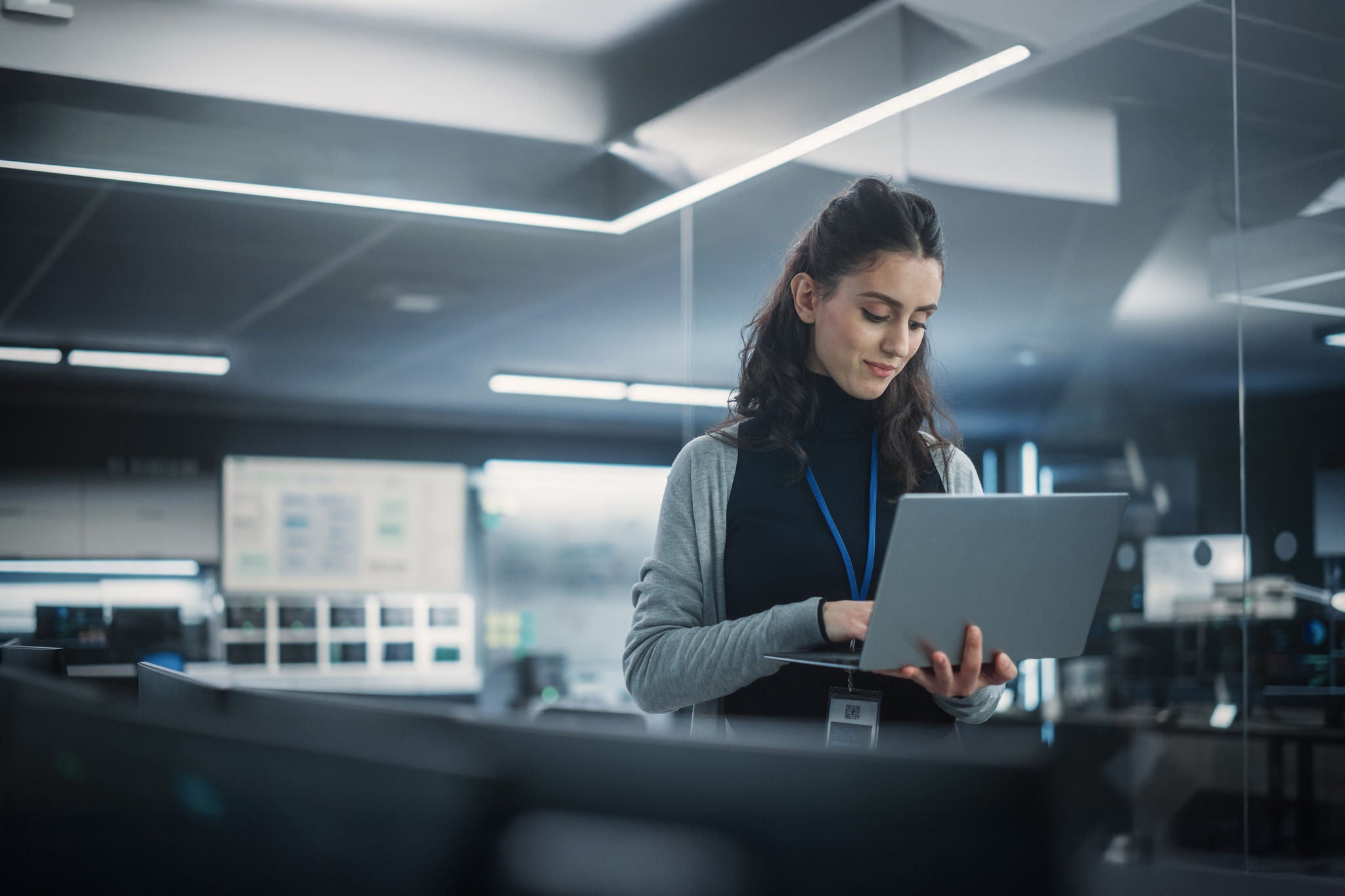 Person arbeitet mit Laptop in einer modernen, technologie­getriebenen Büroumgebu