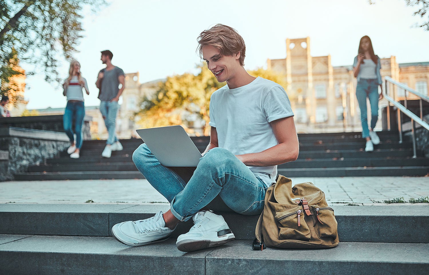 Group of young people are studying together in university. Students outdoors sitting on stairs.