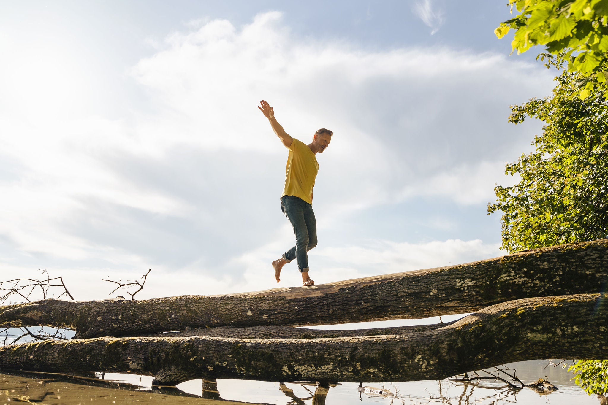 Man walking on fallen tree at lake