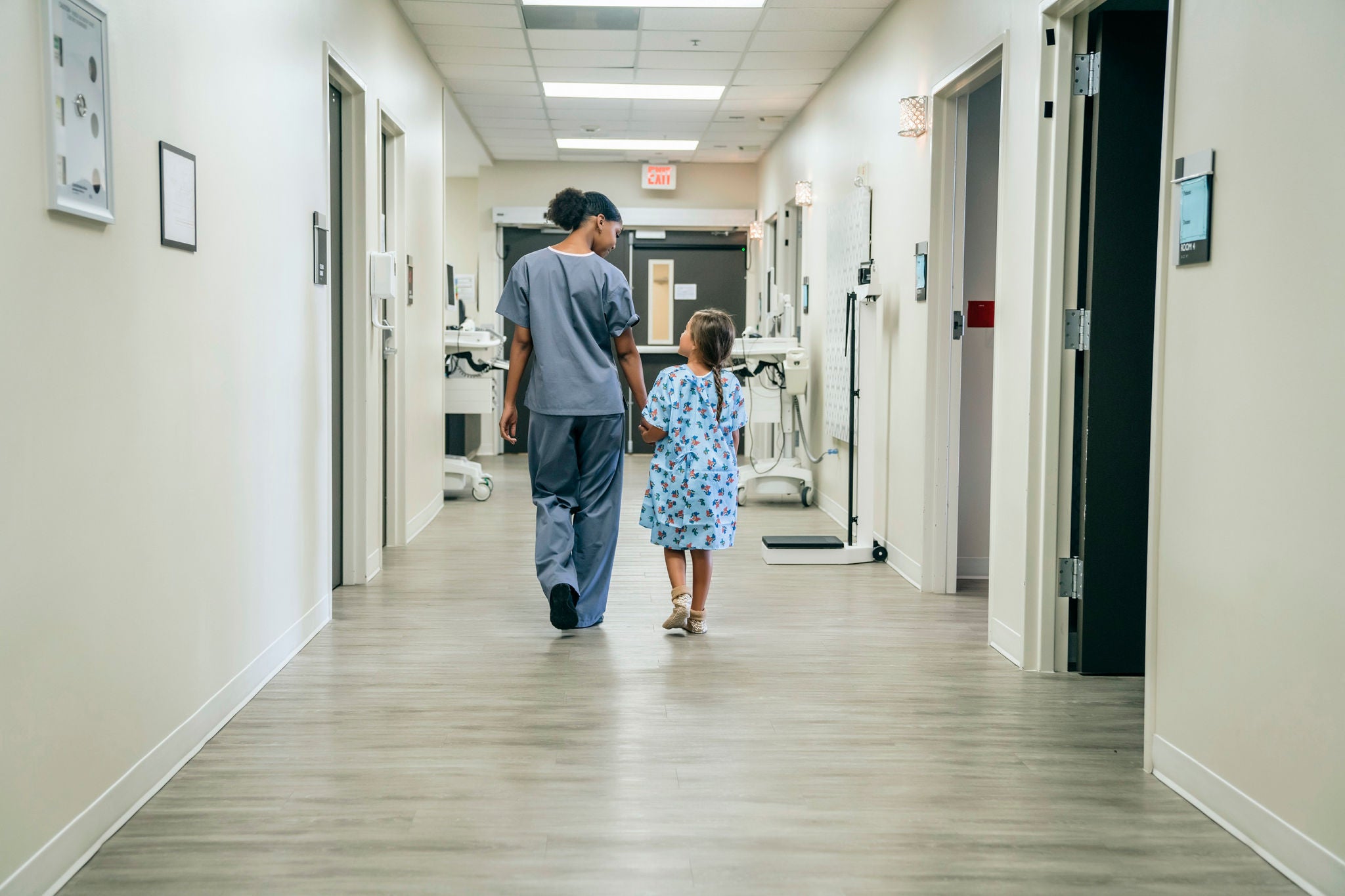 Nurse walking with girl in hospital corridor