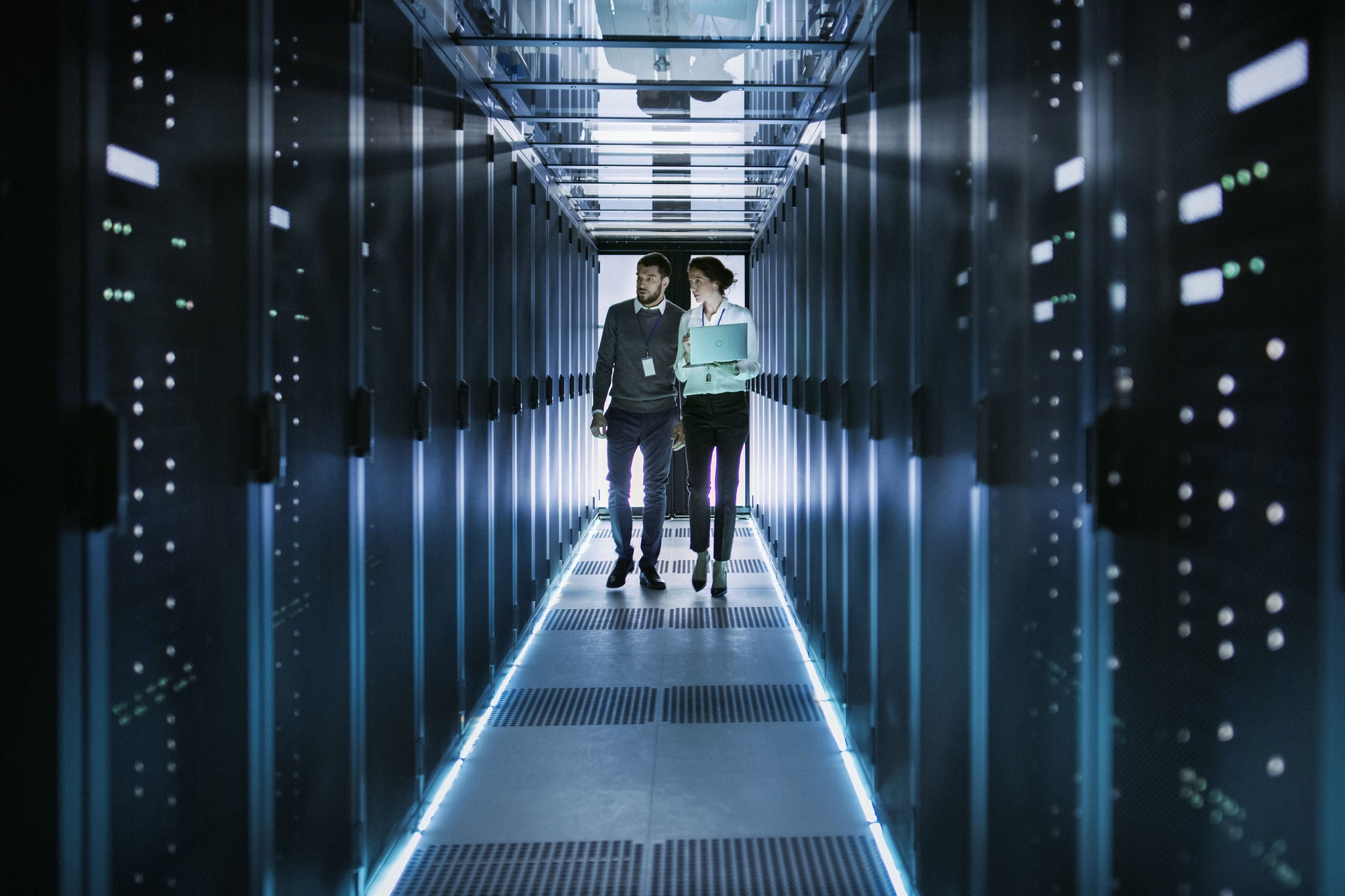 Man and woman walking in a space full of servers