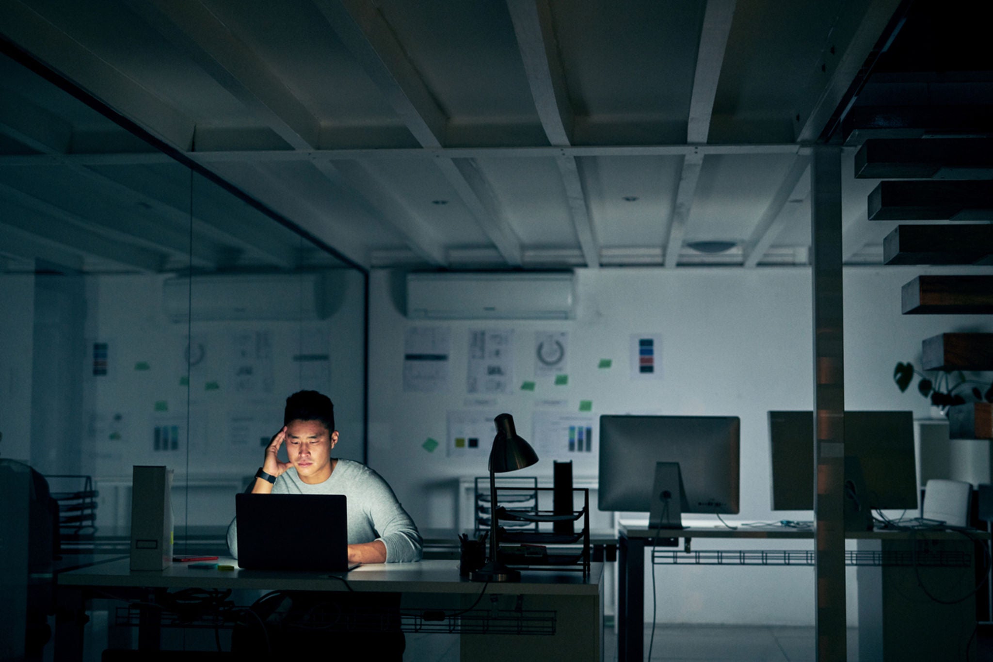 Shot of a young businessman looking stressed during a late night in a modern office