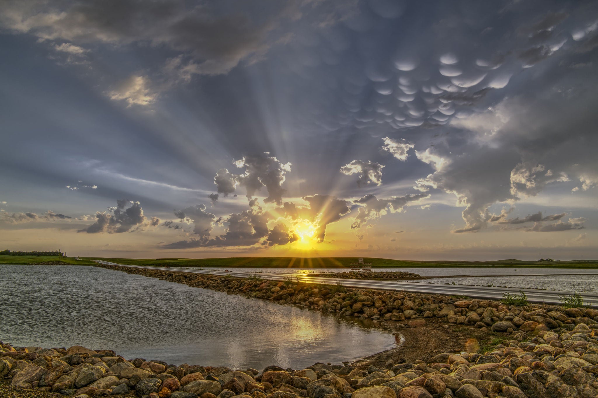 Rays of sunlight shining through clouds with shallow waters in the foreground