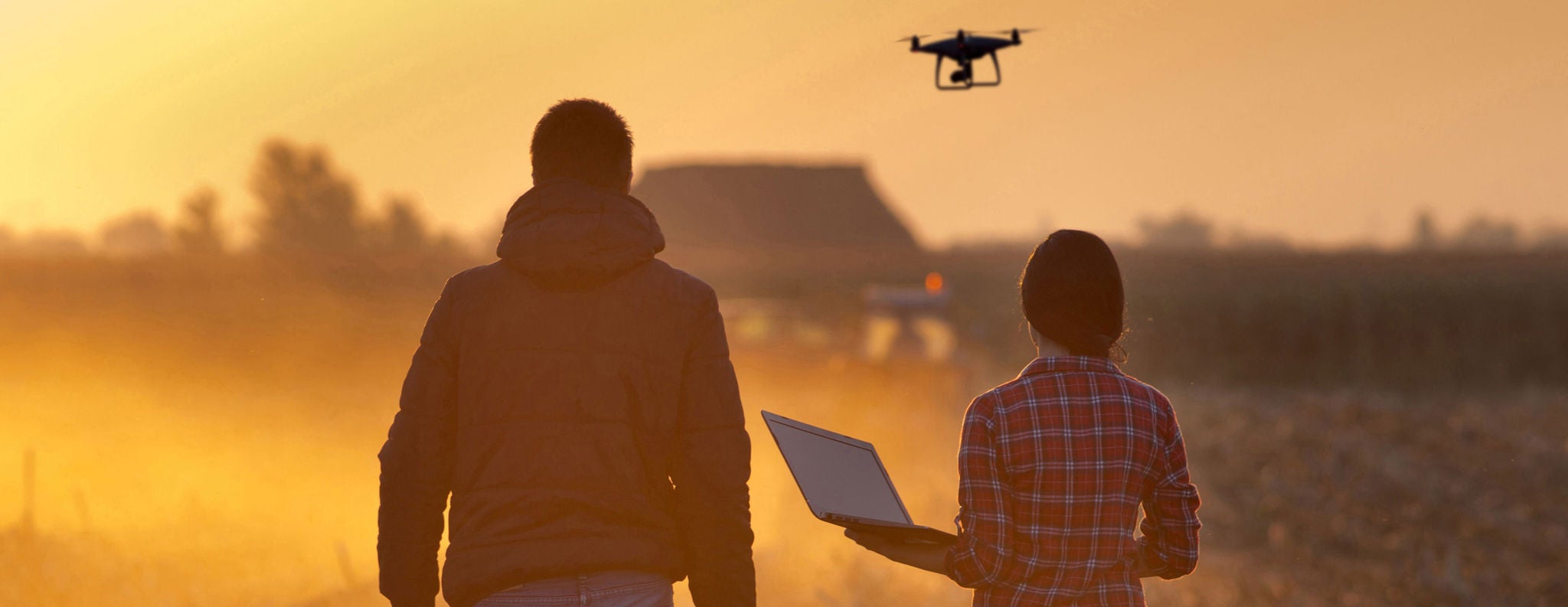 Hombre y mujer conducen drone en un campo