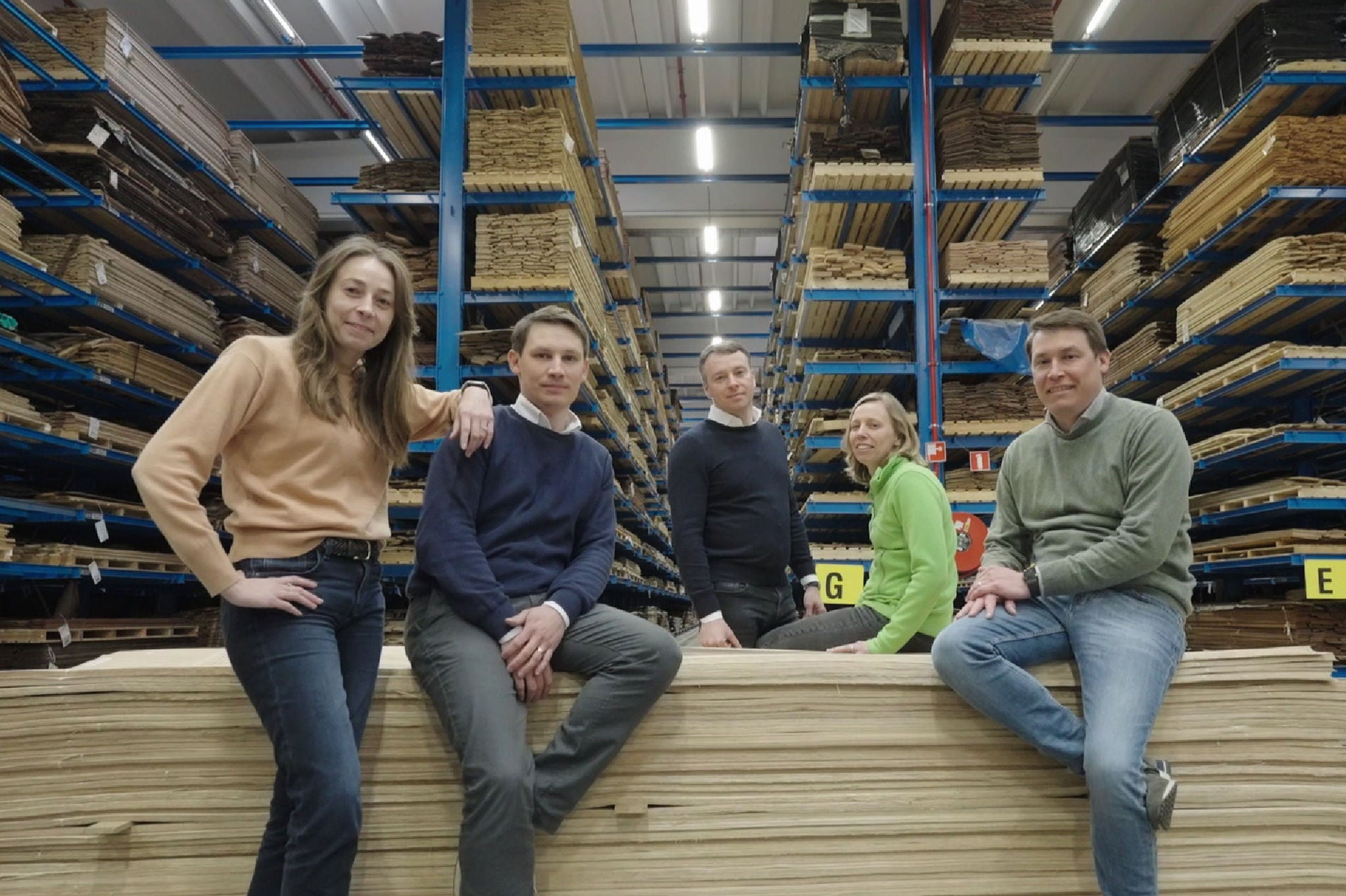 Group of five people sitting on wooden boards 