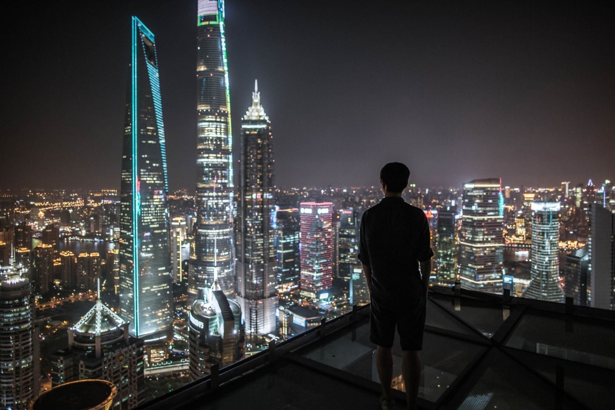 Man admiring city skyline at night from rooftop