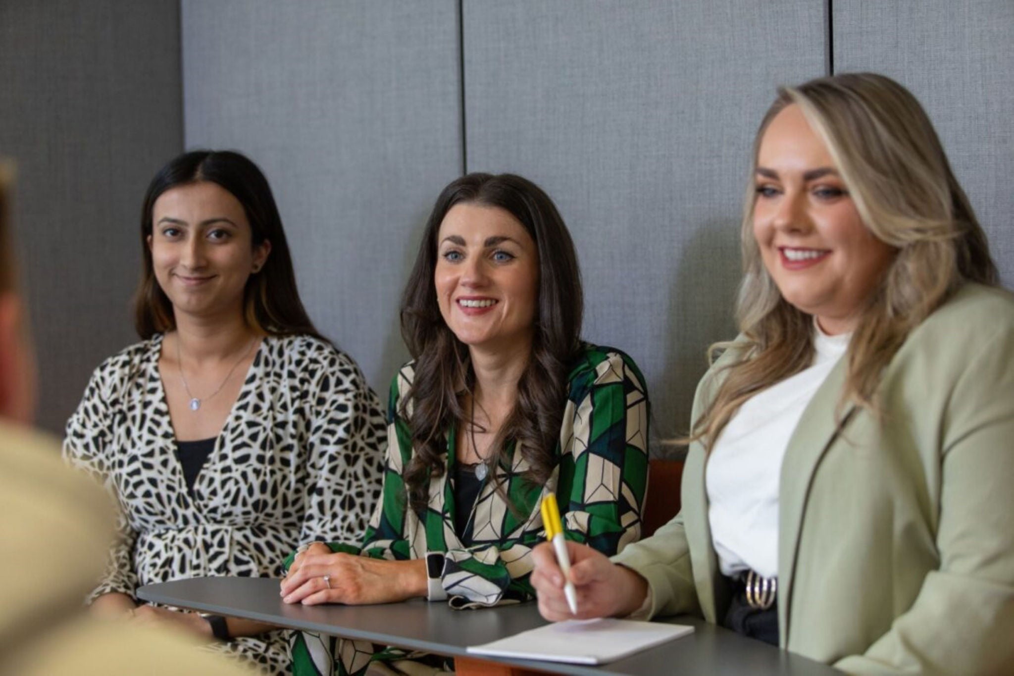 Three EY students sitting at a desk taking notes